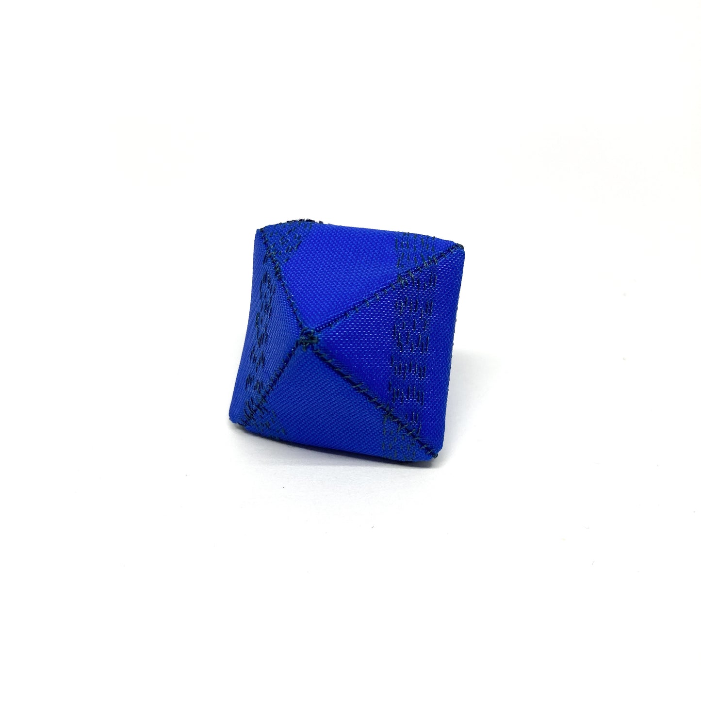 A blue Flagged Ring, a cube-like object with dark seams, sits against a bright backdrop.