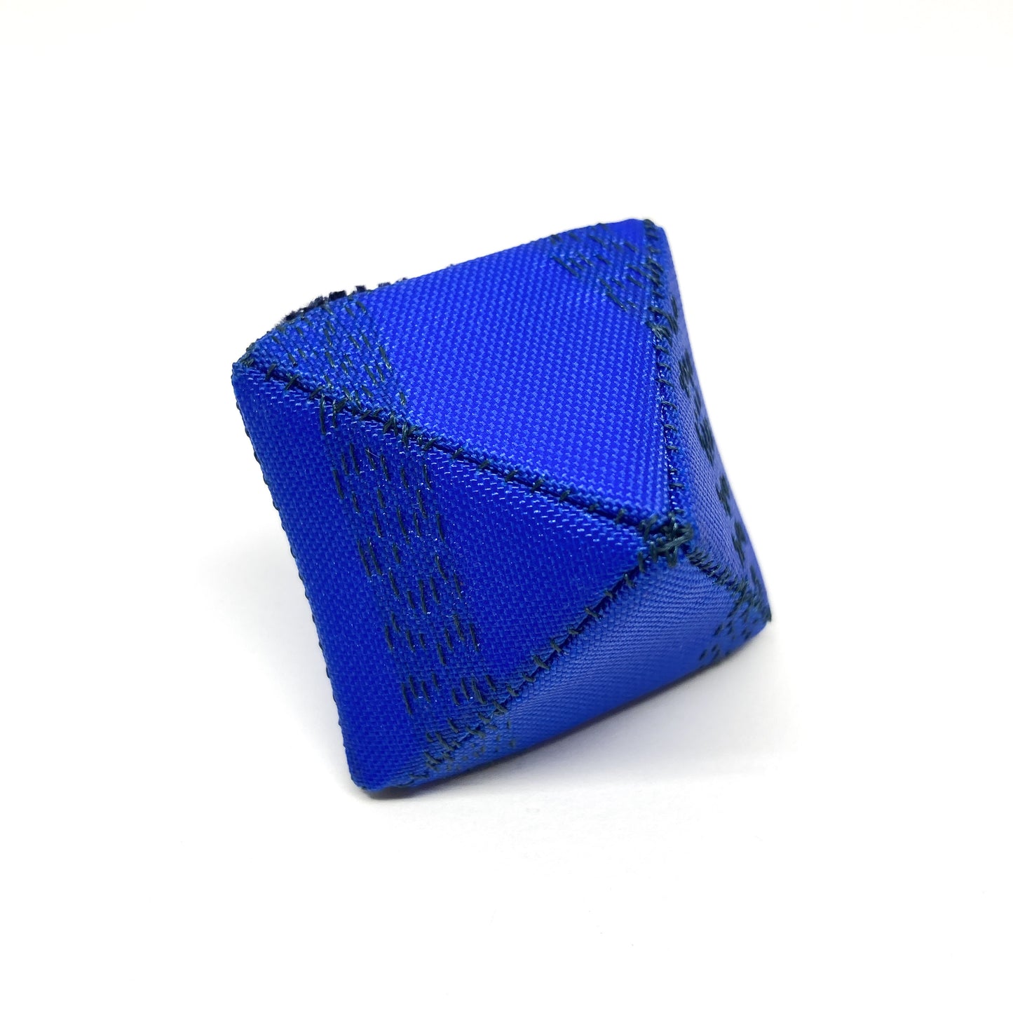 A close-up shows a blue Flagged Ring, a multi-sided object with detailed dark stitching.