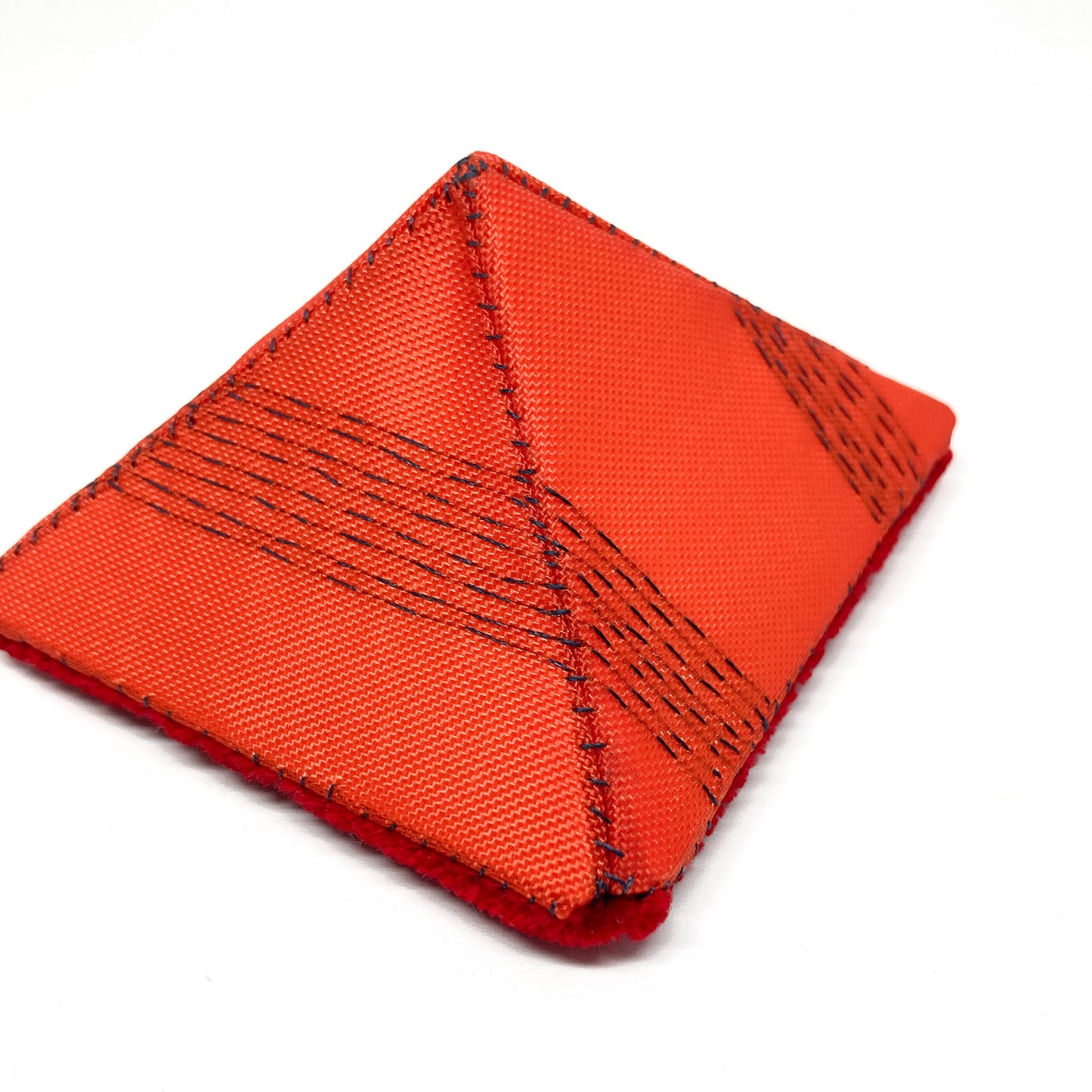 Detailed view of an orange "Flagged Elevensies" brooch showcasing its woven fabric and dark stitching.