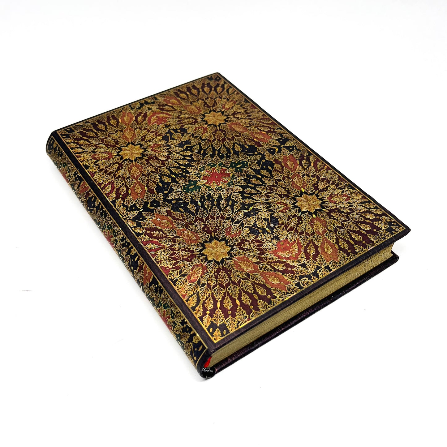 A closed book with a dark cover and ornate gold and red floral patterns.