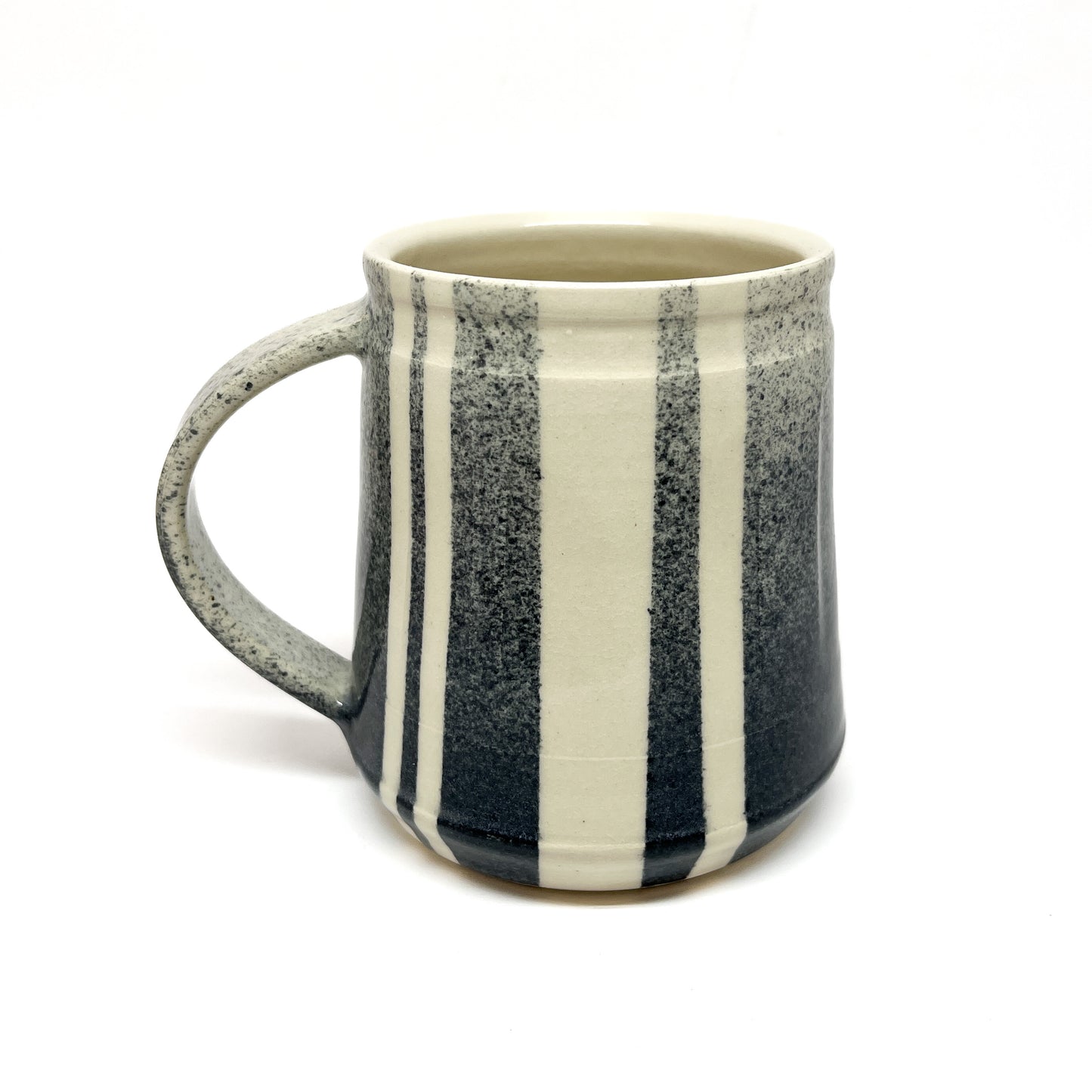 Upright ceramic mug with vertical stripes and a handle.