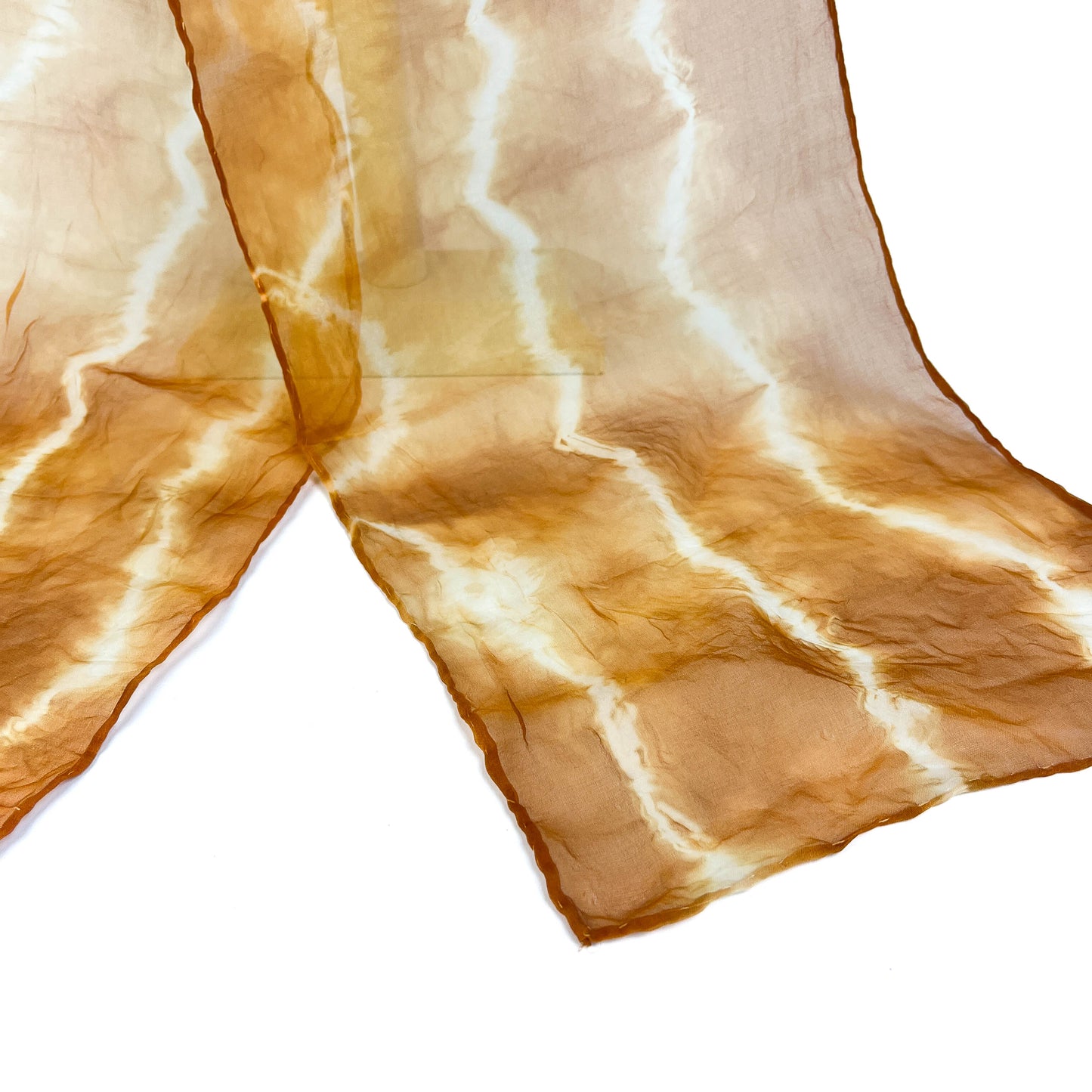 A section of a Walnut Hull silk scarf displays its soft, wavy horizontal shibori tie-dye pattern.