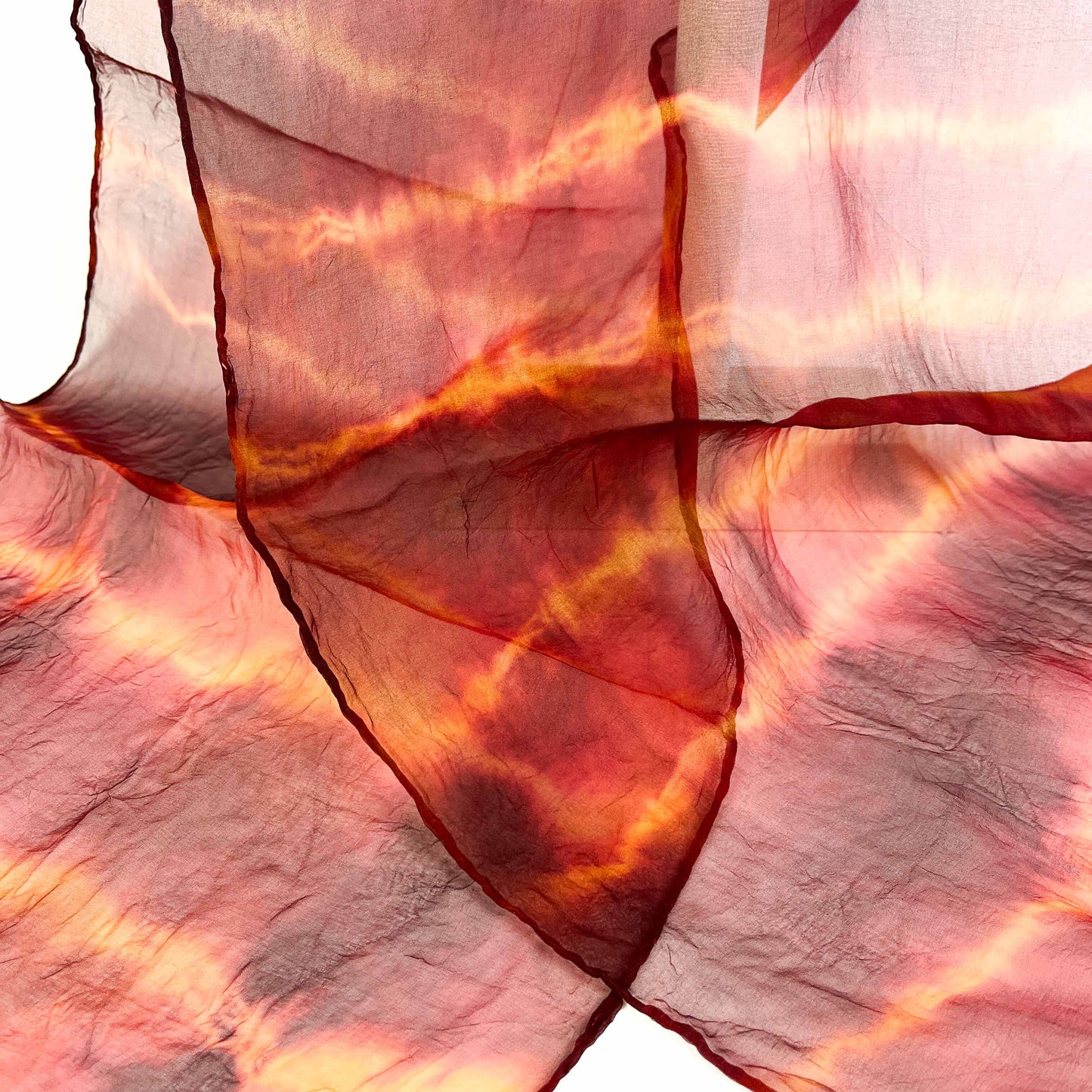 A close-up shows the delicate weave and horizontal tie-dye pattern with subtle texture on a sheer silk scarf.