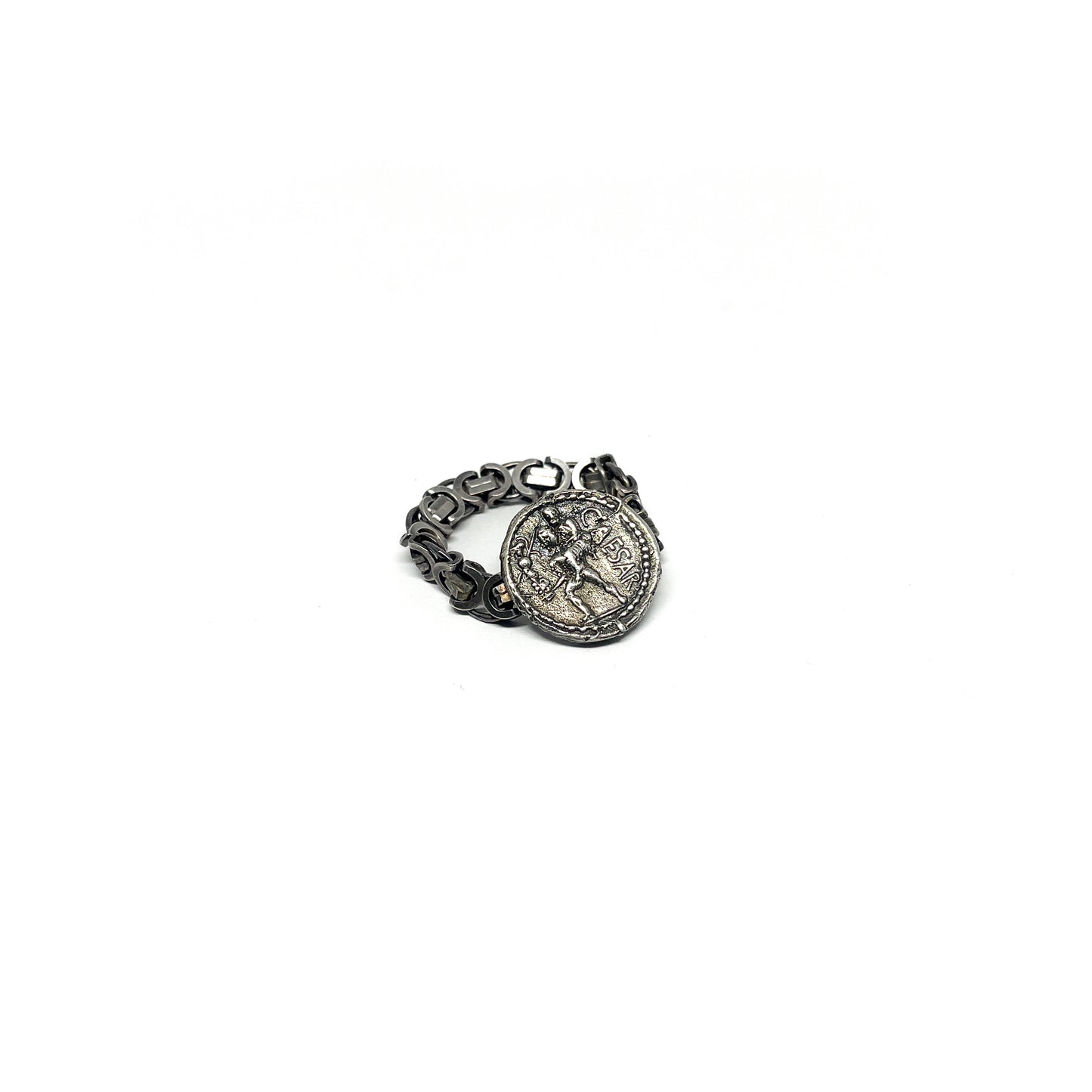 A silver ring featuring an embedded, aged coin with a figure and inscription, attached to a chain-link band.