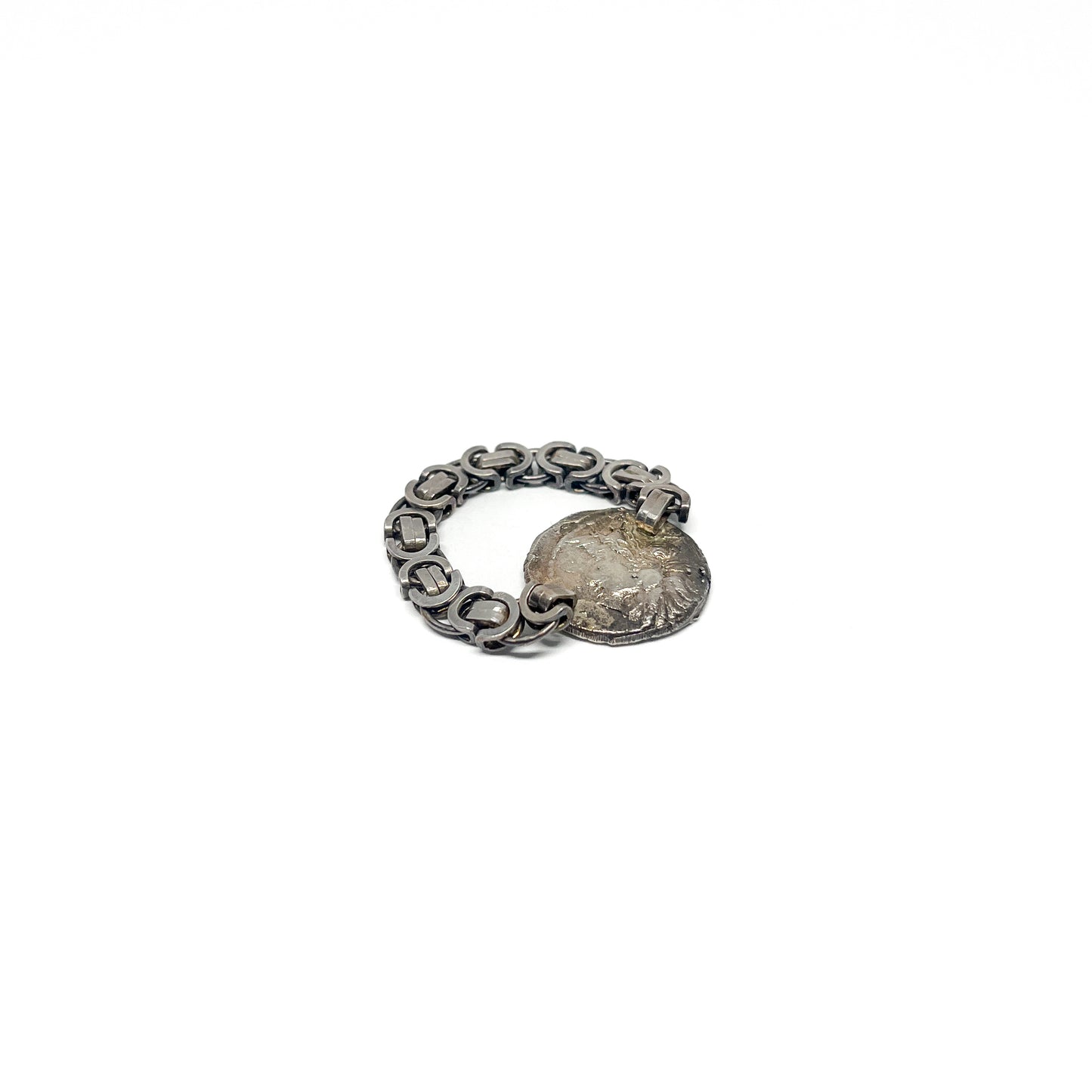 Angled view of a silver ring with a chain-link band and an attached, tarnished coin featuring a raised design.