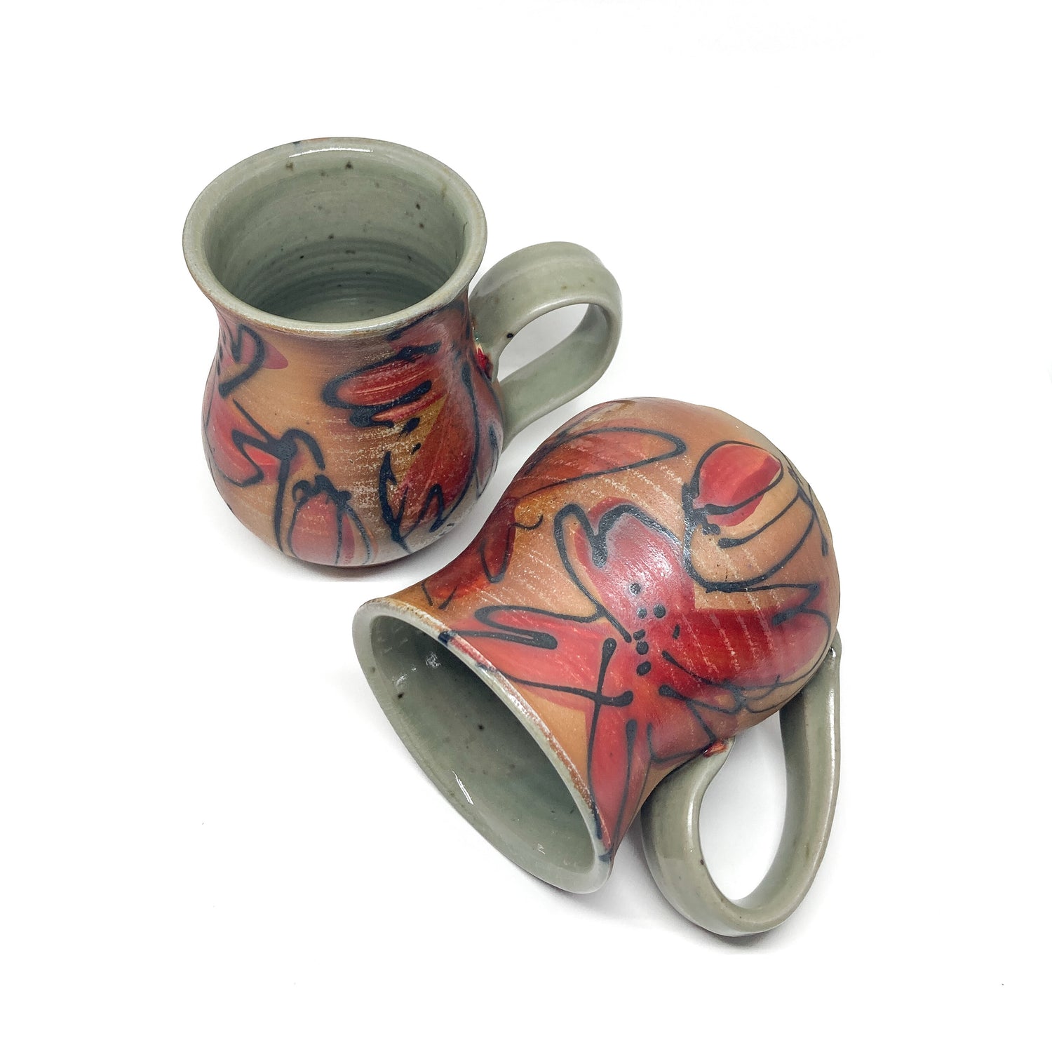 Two ceramic mugs with hand-painted floral designs. The mugs have handles and a slightly flared shape.