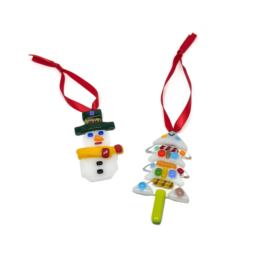 Two glass Christmas ornaments: a snowman and a tree, each with a red ribbon for hanging.