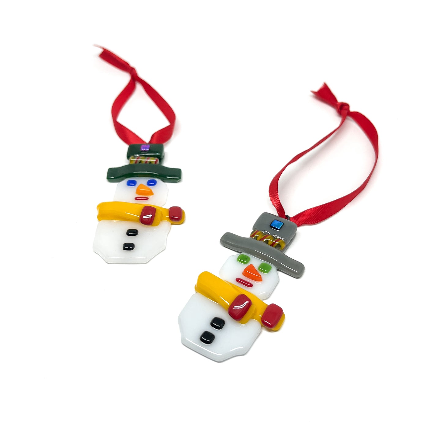 Two glass snowman ornaments with colorful details, each with a red ribbon for hanging.