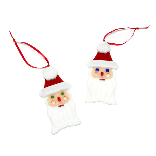 Two glass Santa ornaments with red ribbons, viewed from above.