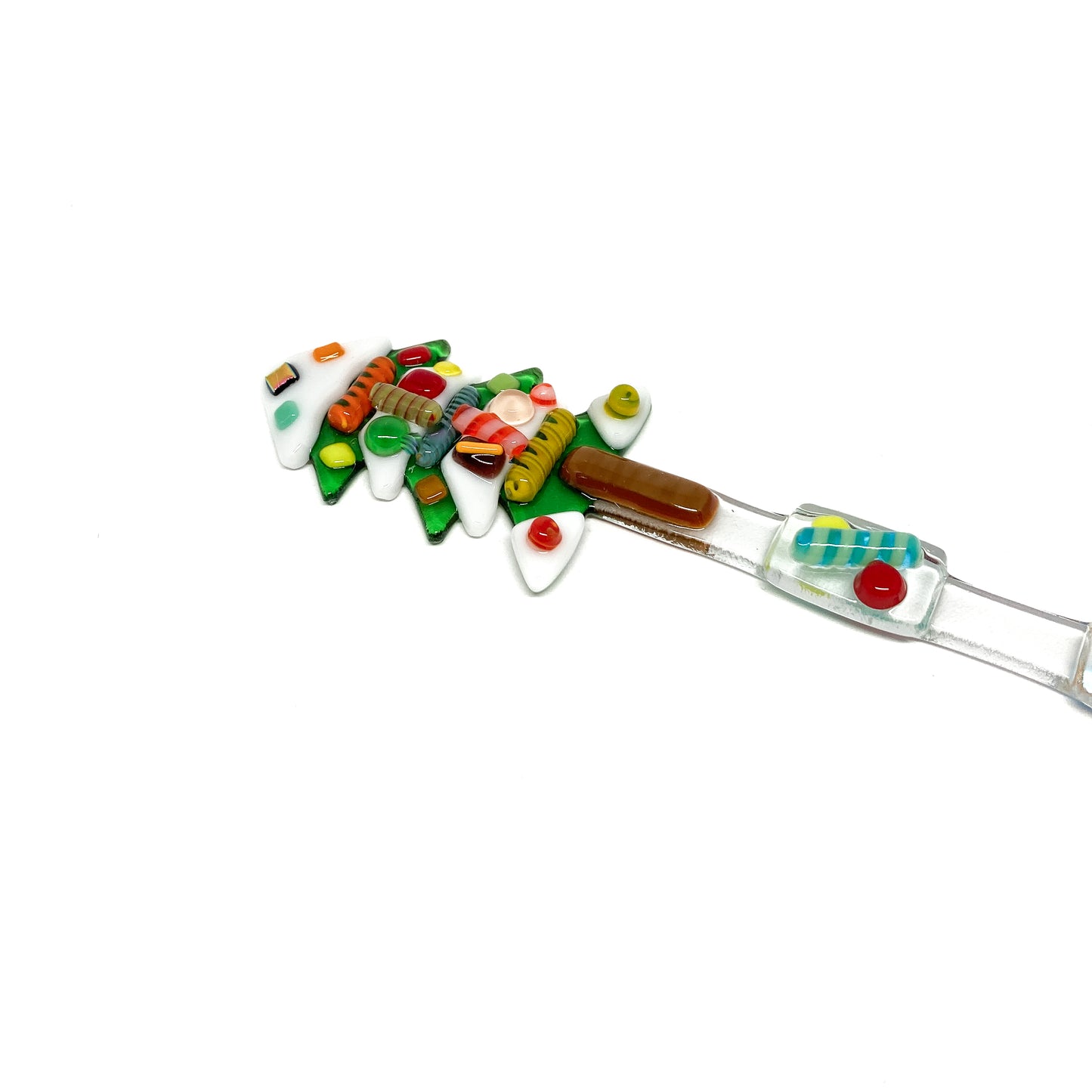 A glass stir stick shaped like a Christmas tree, decorated with colorful glass pieces.