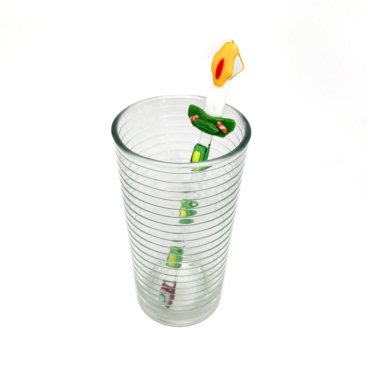 A glass stir stick shaped like a candle inside a clear glass.