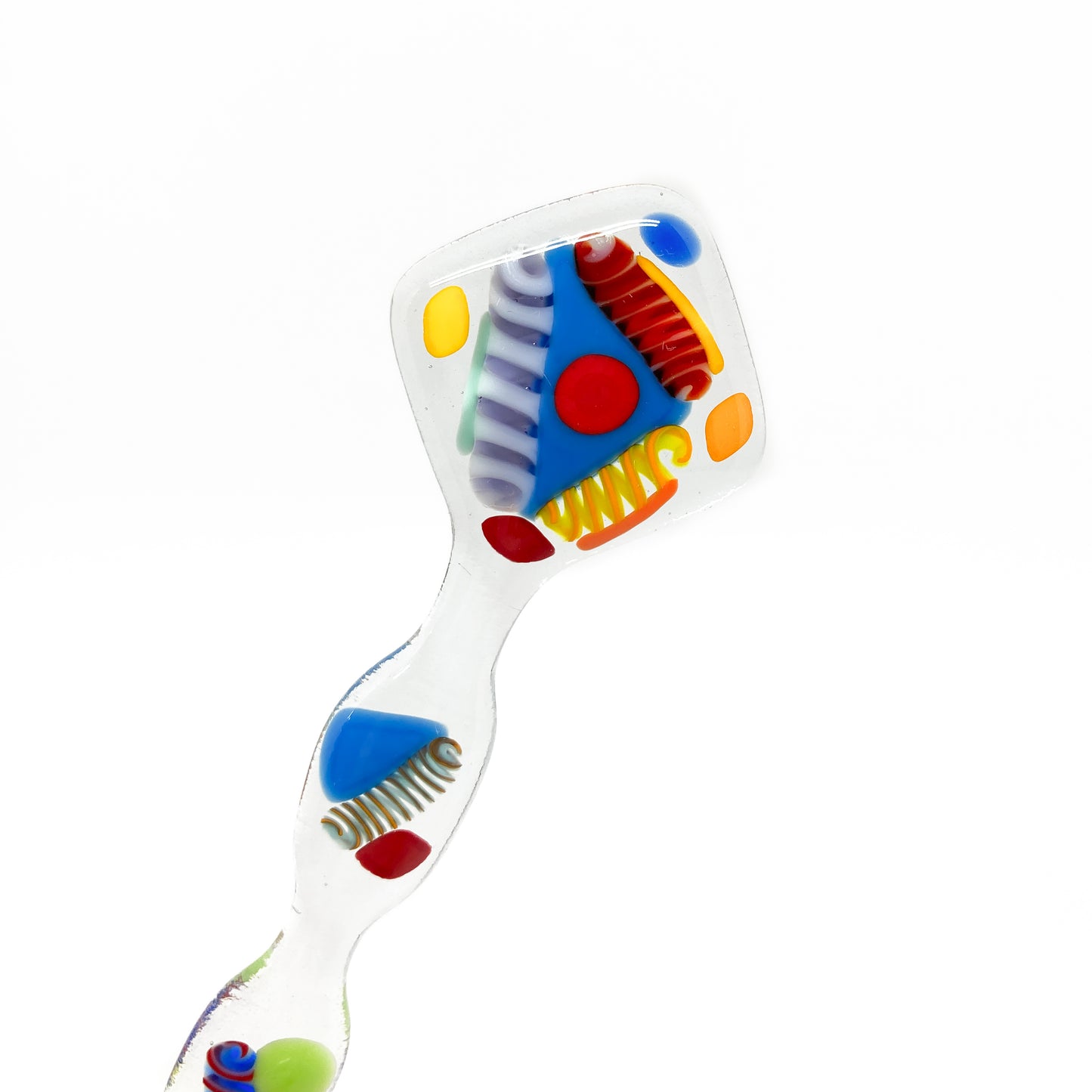 A glass stir stick with a colorful abstract design, viewed from above.