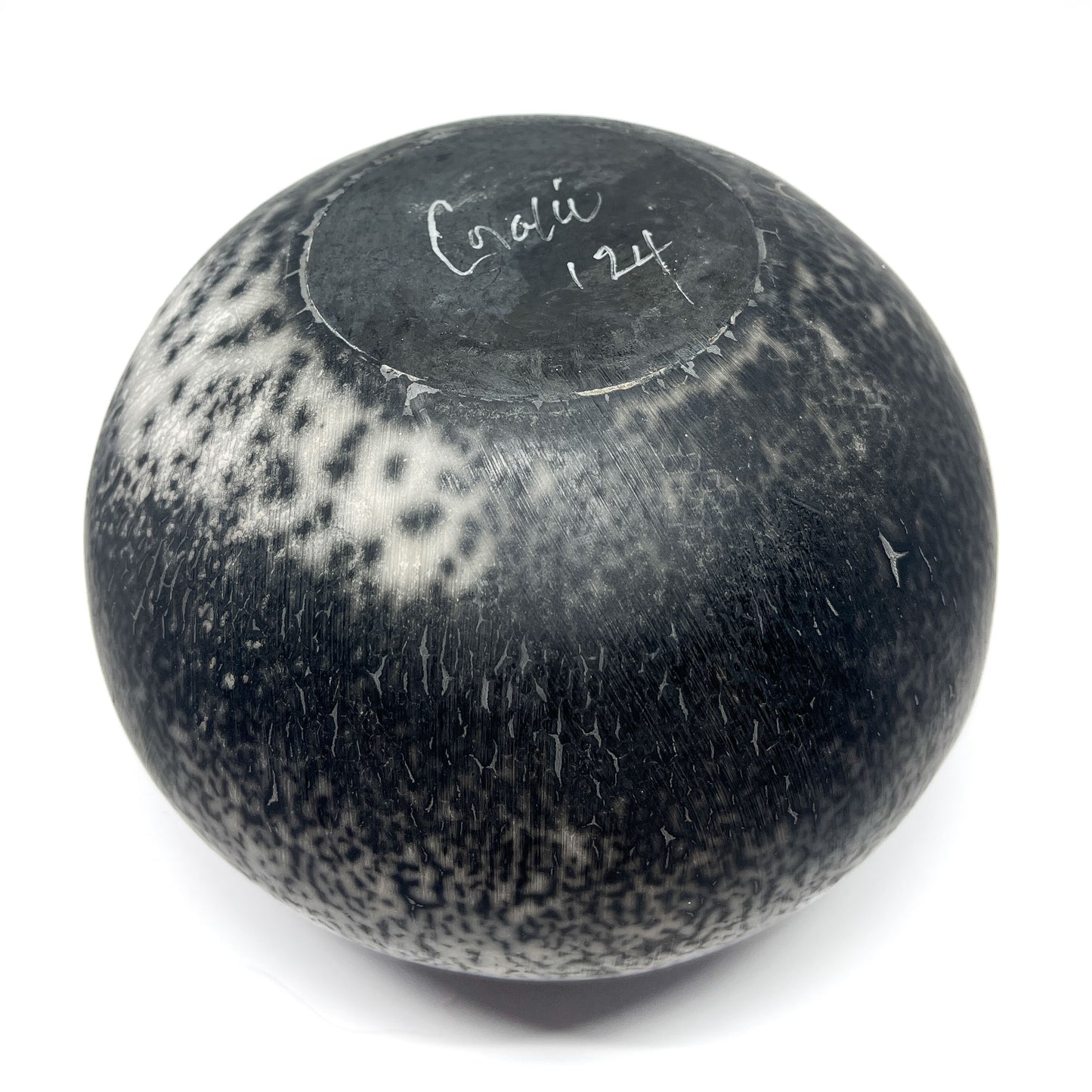 Round ceramic vase with a textured, crackled black and white glaze and handwritten text on the top.