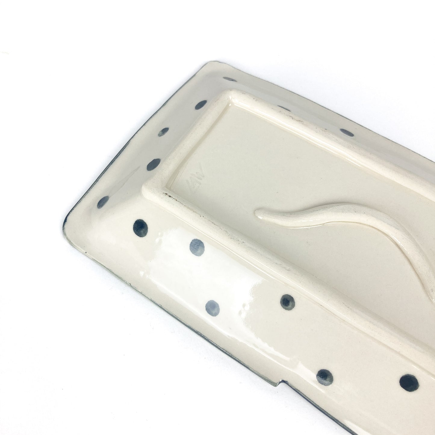 Side view of rectangular ceramic platter showing shallow form, polka dot accents, and gentle slope.