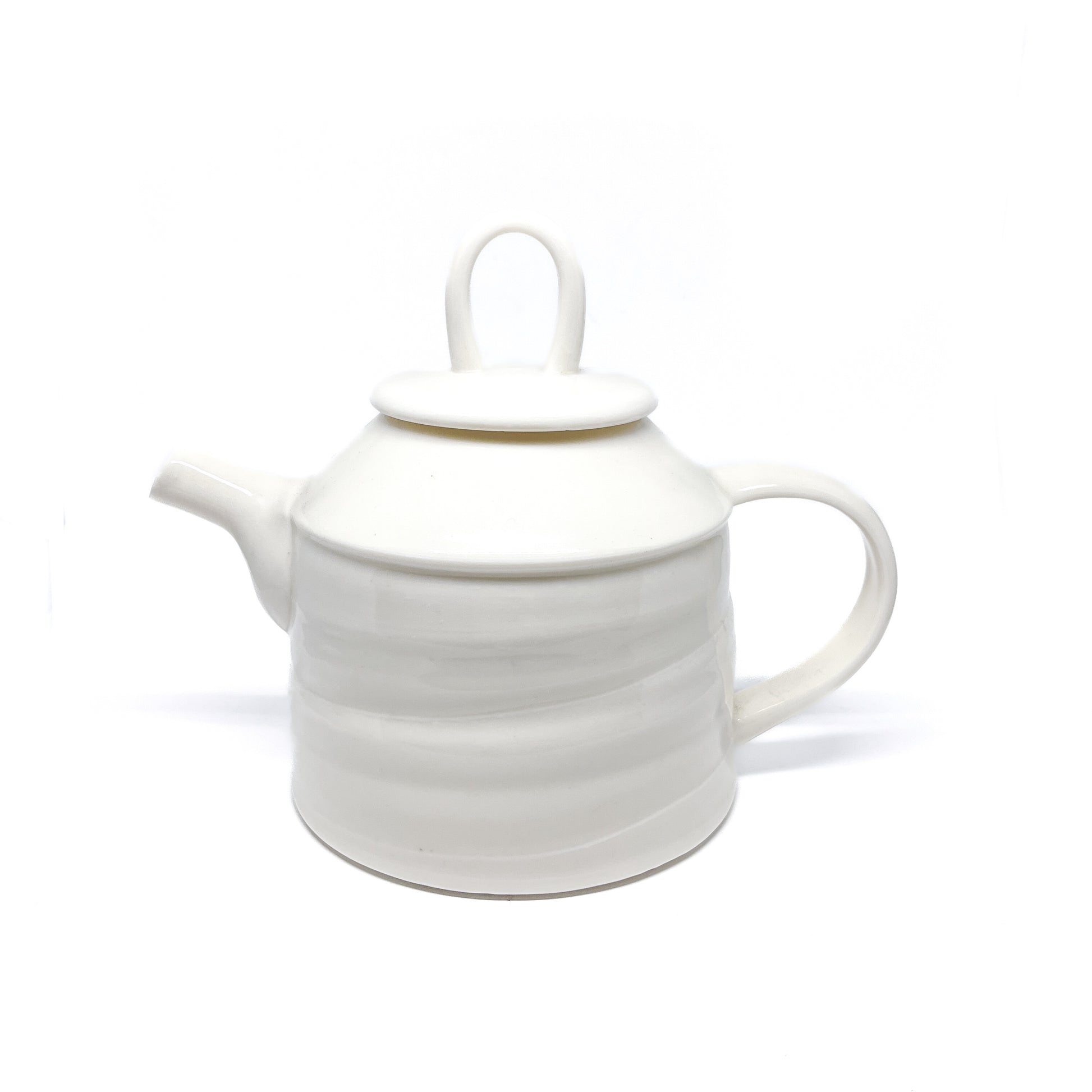 A white ceramic teapot with a lid, spout, and handle, featuring horizontal ridges around the body.