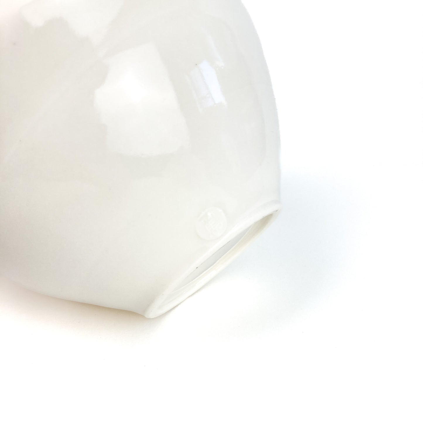 A close-up of the base of a white ceramic bowl, showing a small circular mark