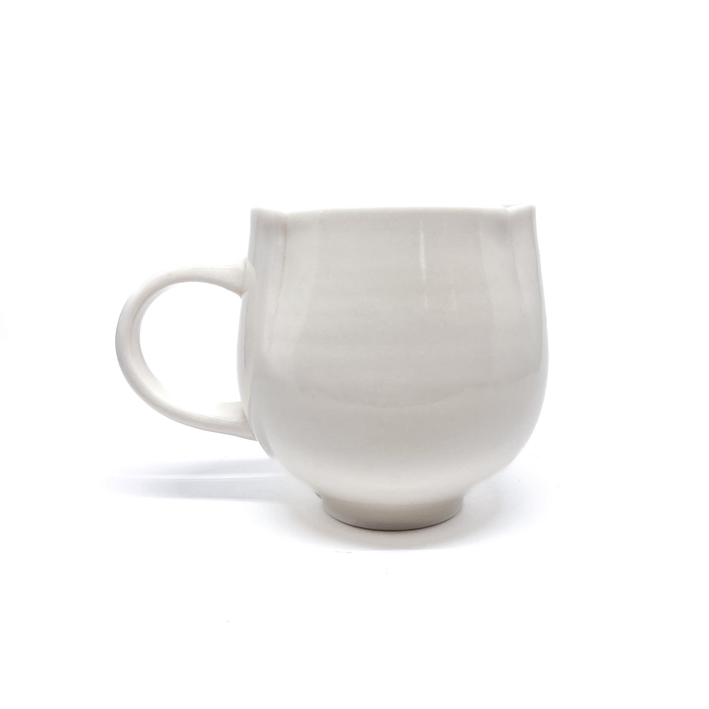 A white ceramic mug with a handle and a slightly flared rim.