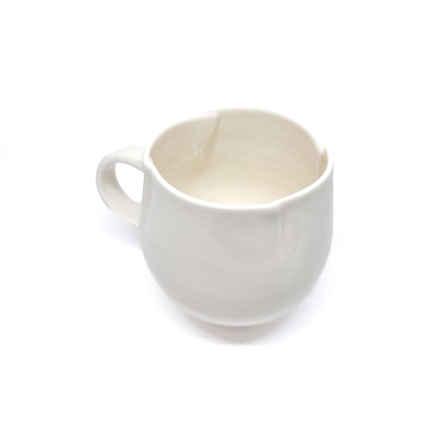 A white ceramic mug with a handle and a slightly flared rim, seen from above.