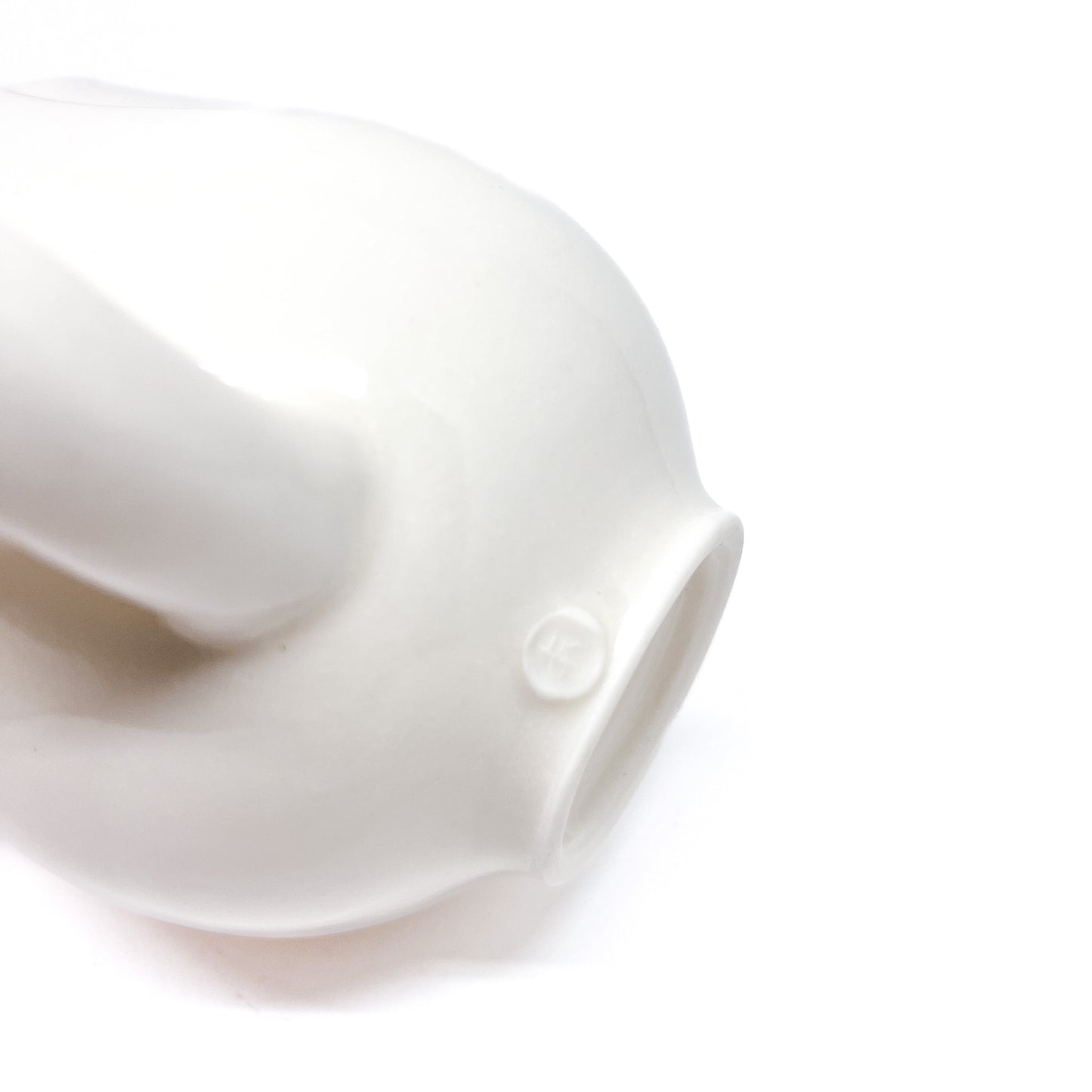 The bottom of a white ceramic mug with a handle, showing a small circular mark.