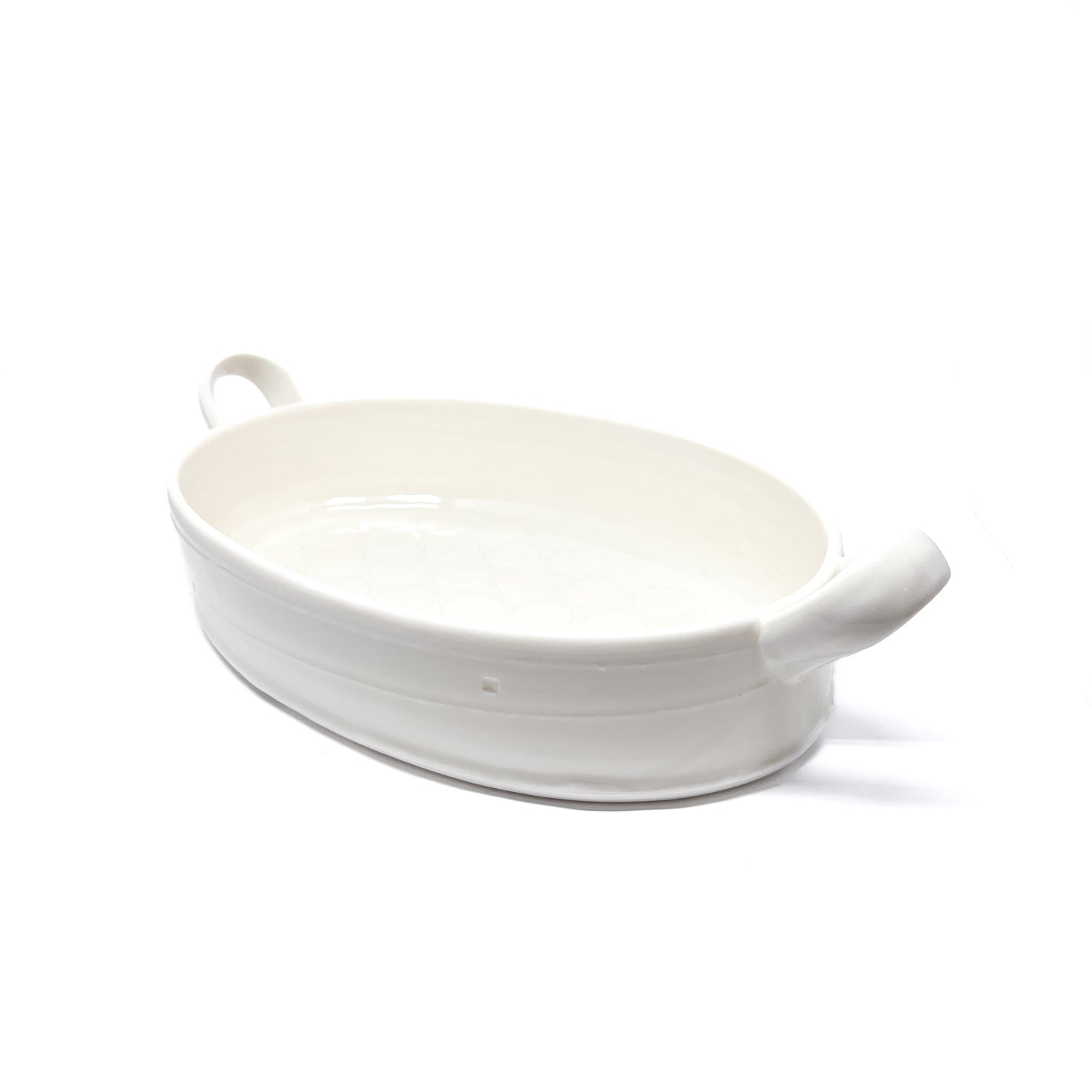 A white oval ceramic casserole dish with handles on each side.