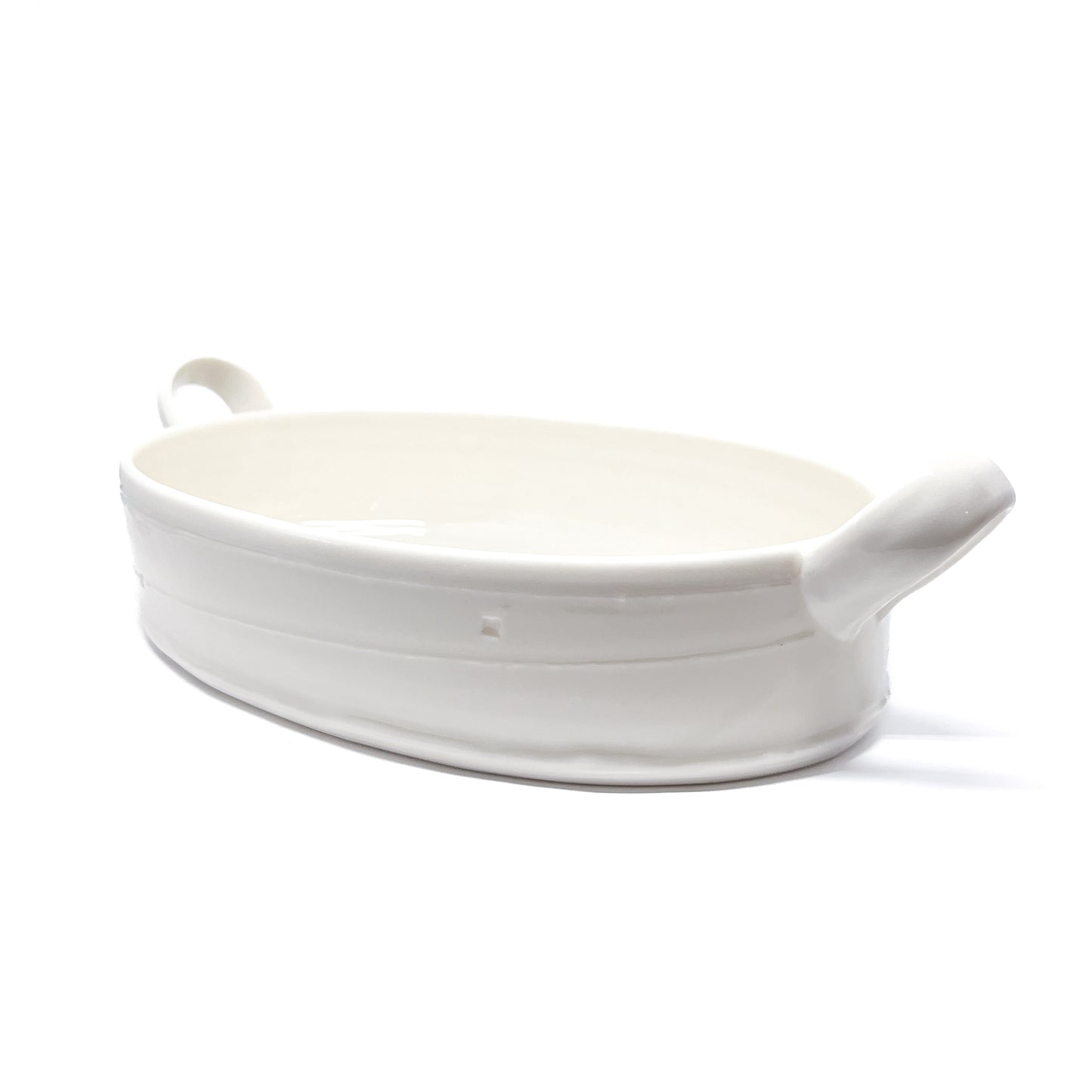 A white oval ceramic casserole dish with handles on each side.