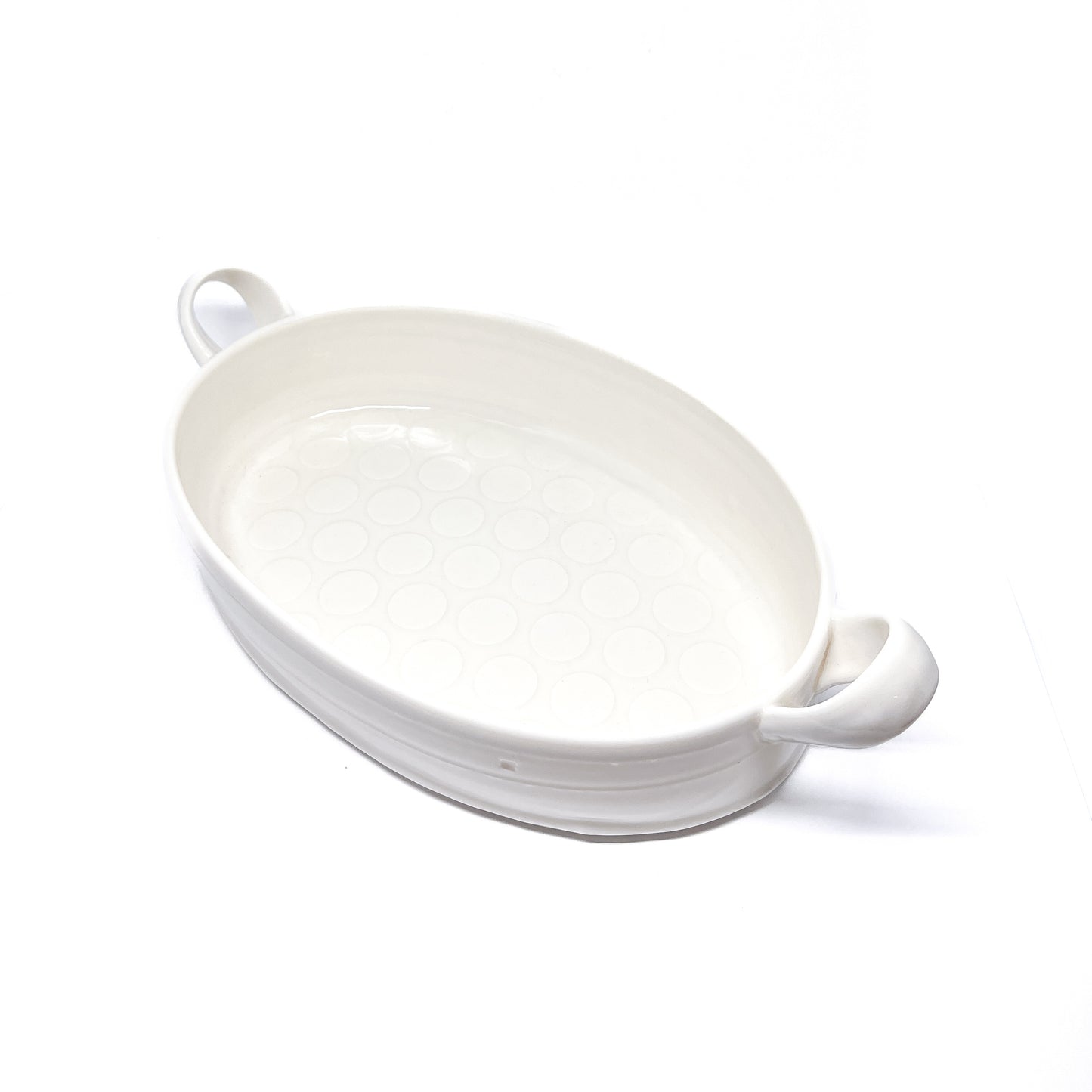 A white oval ceramic casserole dish with handles on each side.