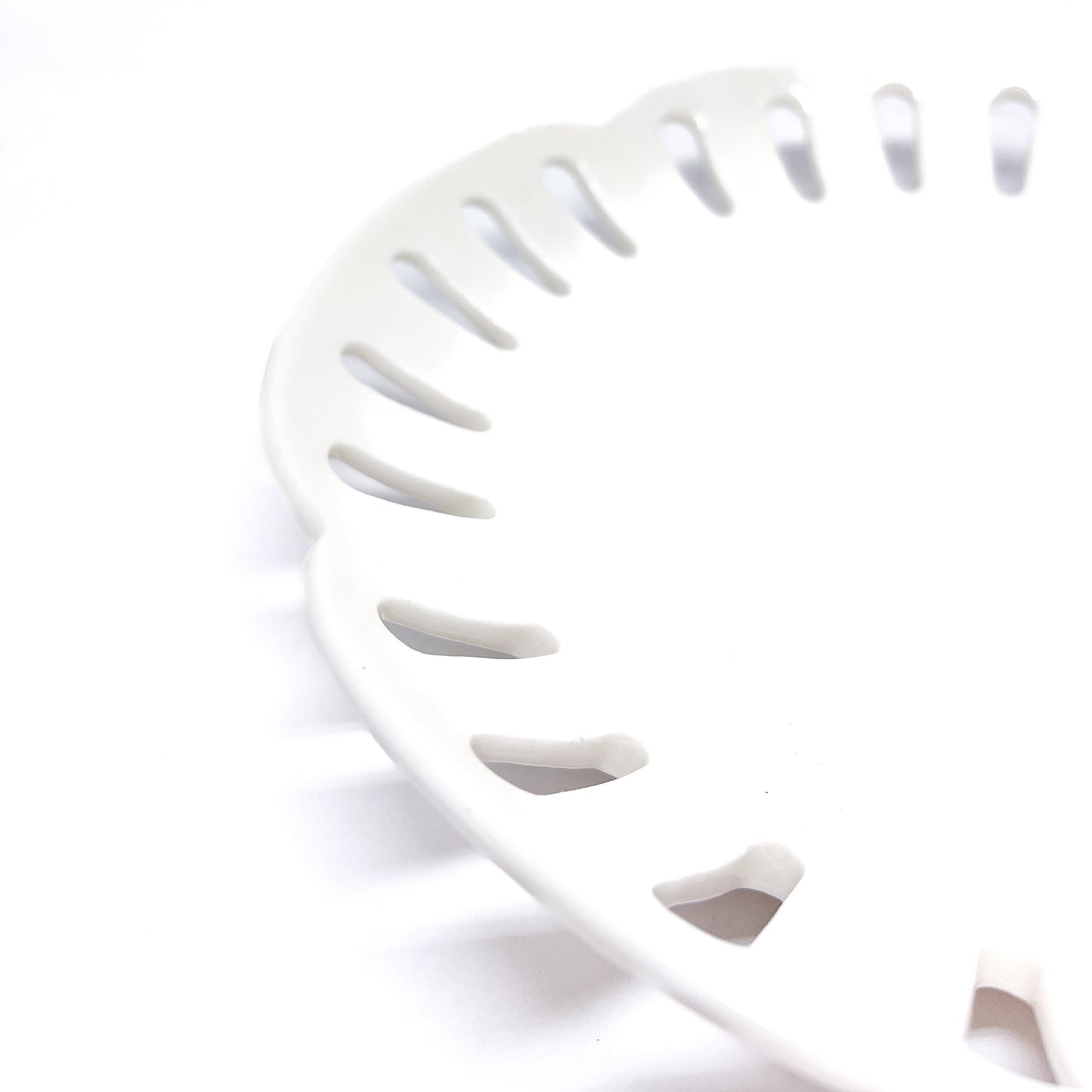 A close-up of a white ceramic plate with decorative cut-outs around the edge, showing the texture and design.