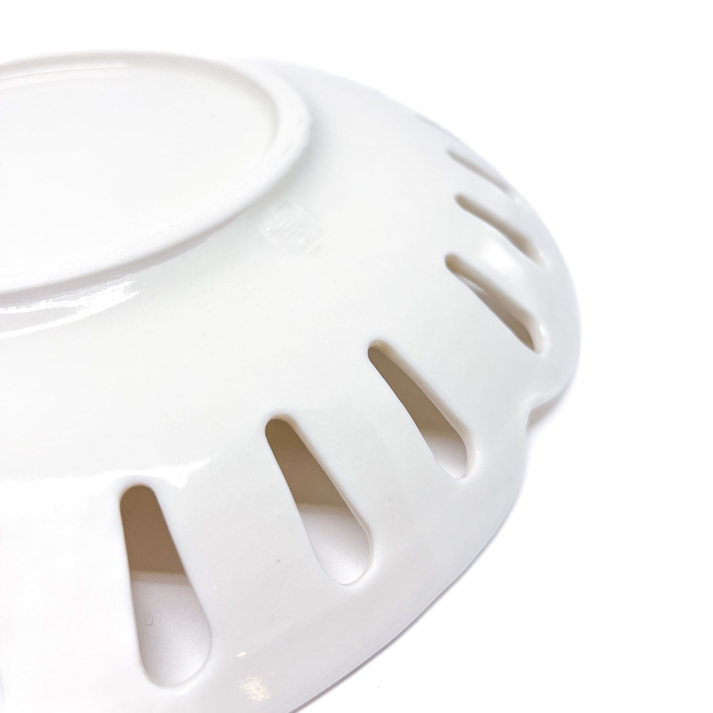 A close-up of a white ceramic plate with decorative cut-outs around the edge, seen from a low angle.