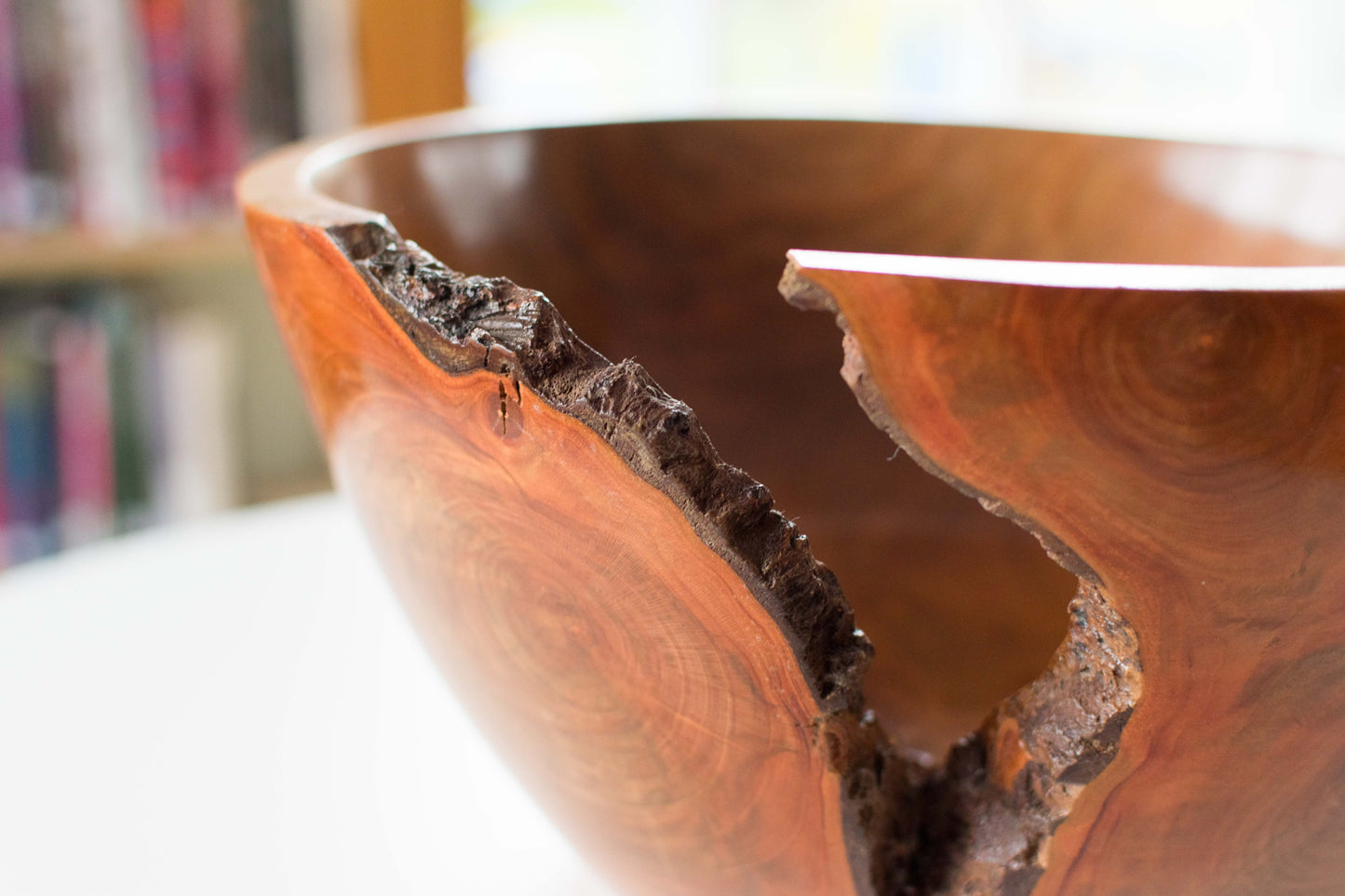 A close-up view of a wooden bowl with a natural crack and rough texture, showing wood grain and a polished finish.