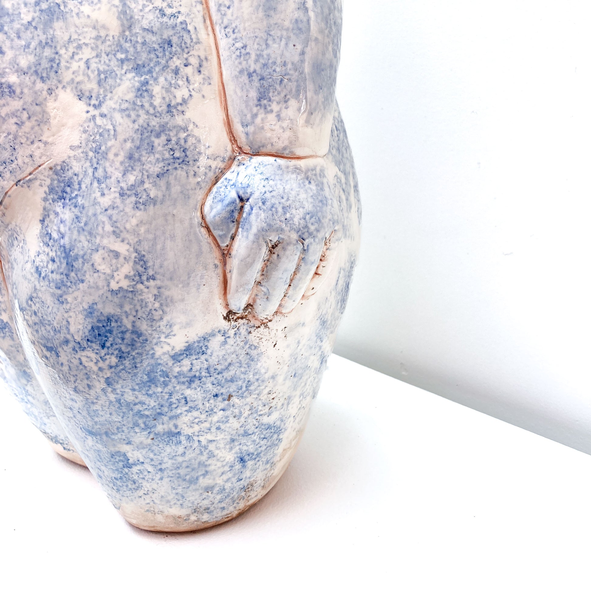 A close-up of a baby sculpture hand with blue paint on its body.