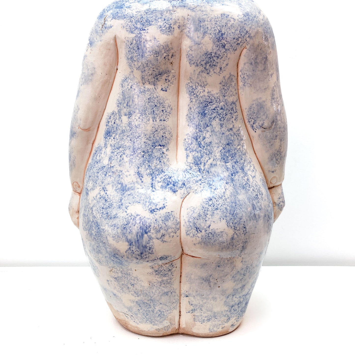 A baby sculpture rear view with blue paint on its body.