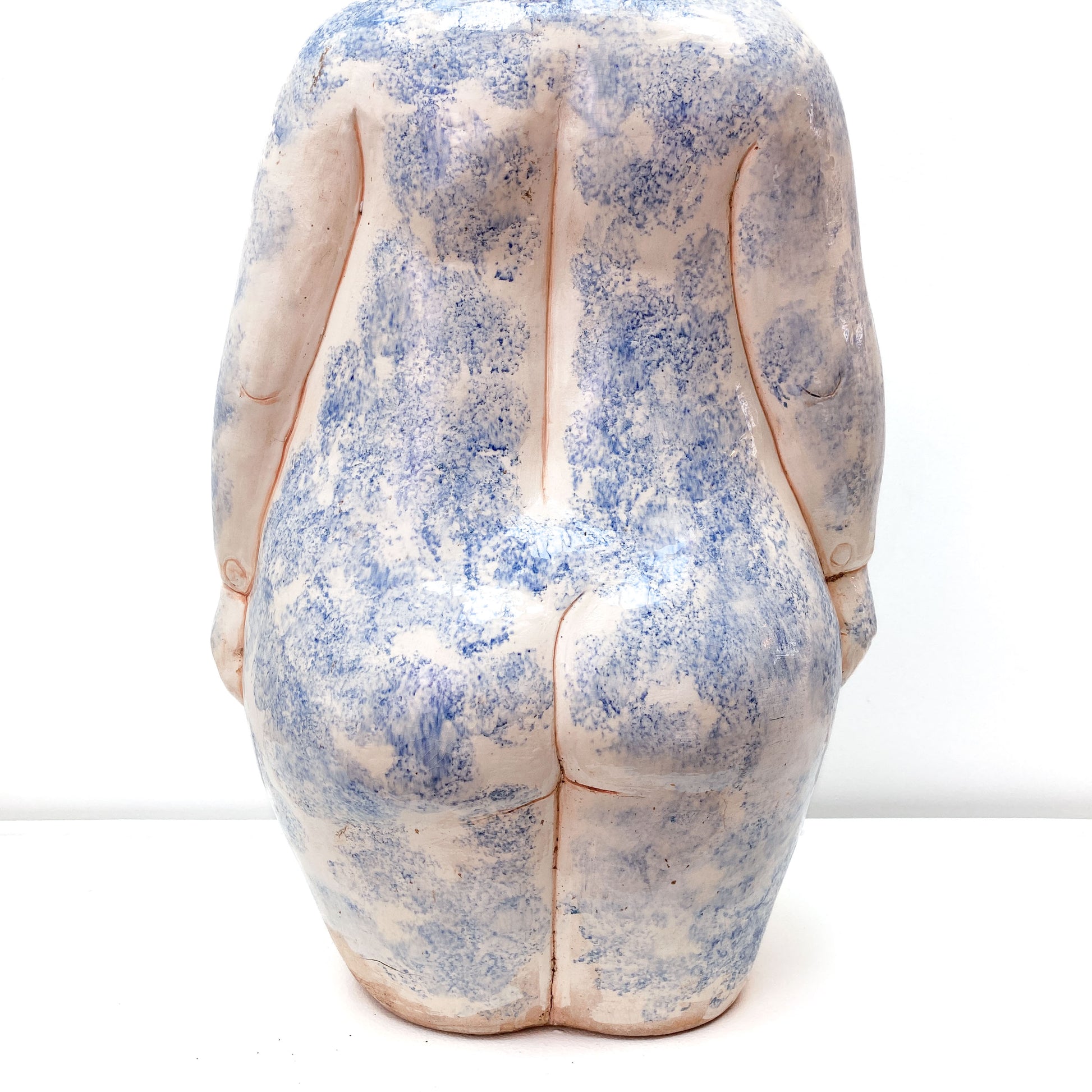 A baby sculpture rear view with blue paint on its body.