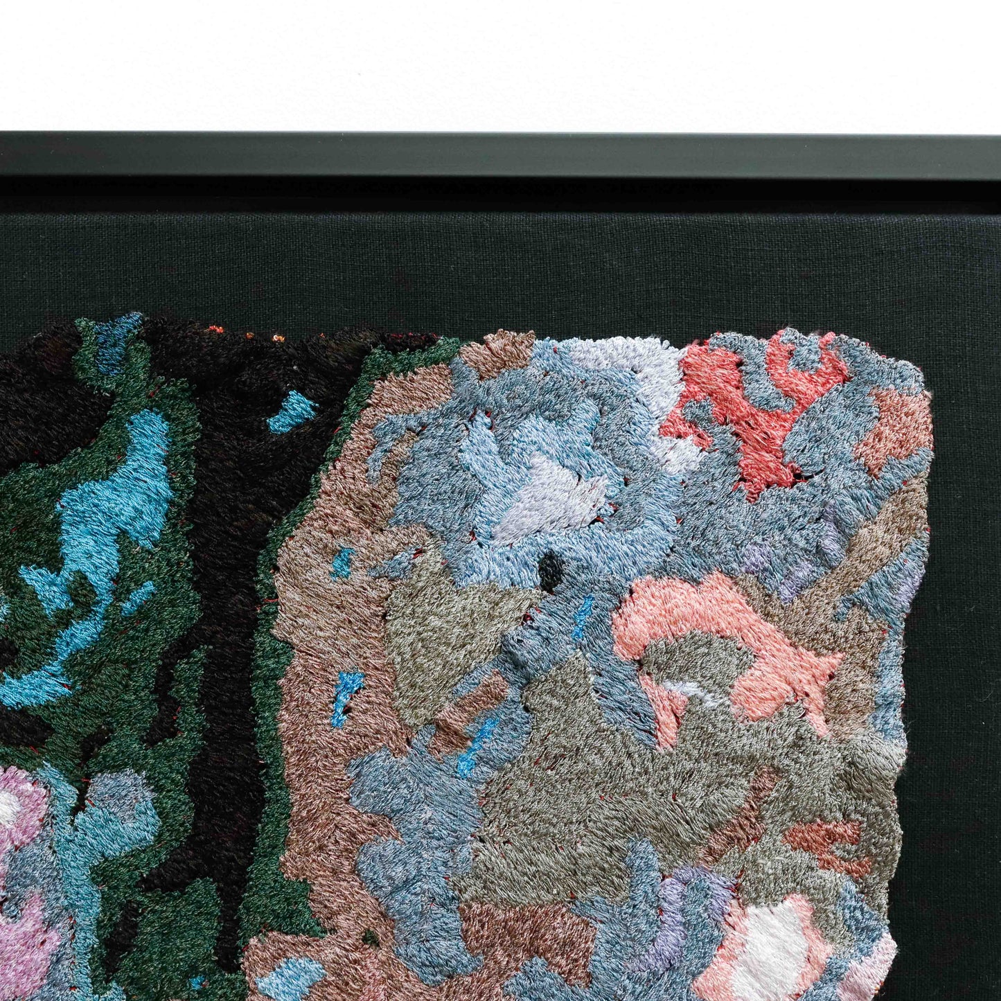 Close-up of a thread tapestry, showcasing detailed embroidery and colorful thread stitching in an abstract design.