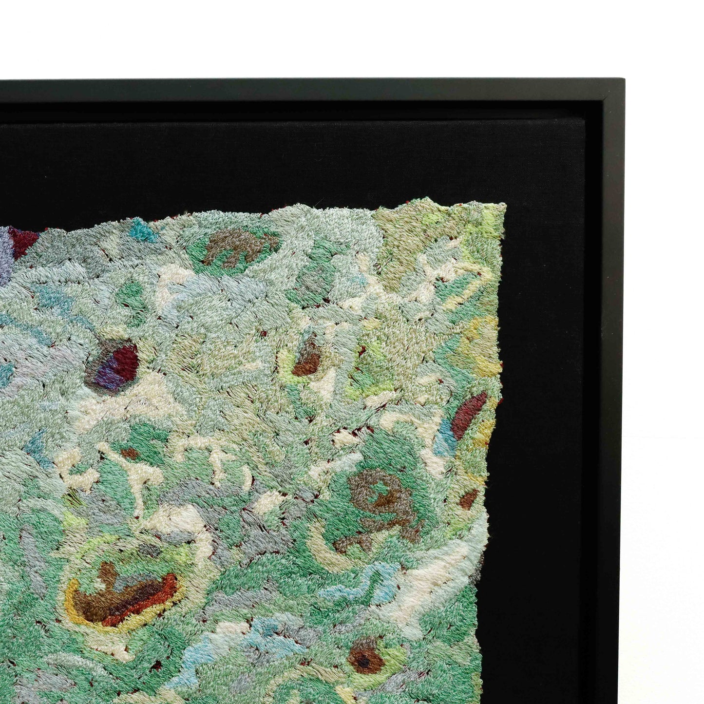 Framed thread painting close-up, showcasing intricate stitching and colorful thread in a textured embroidery design.