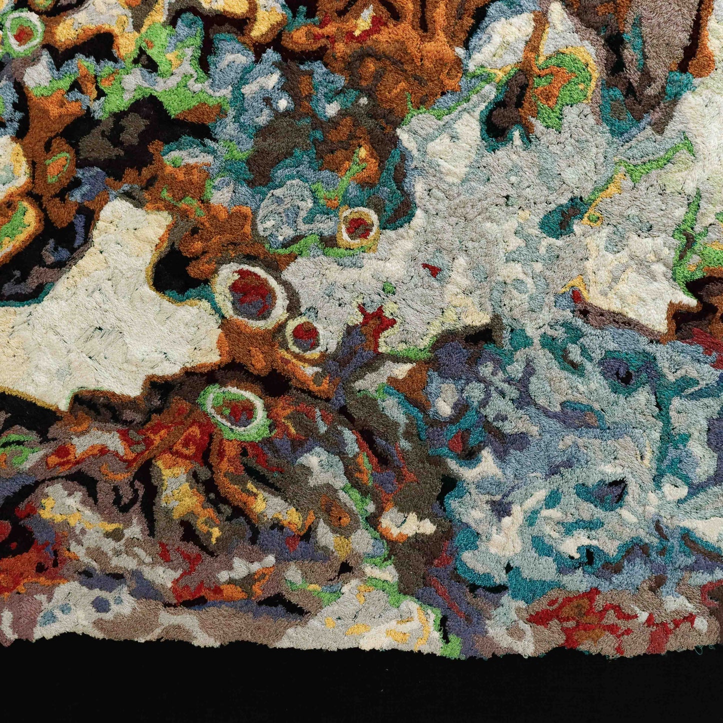 A detailed thread painting with colorful thread creating an abstract, textured pattern. Intricate stitching is visible.
