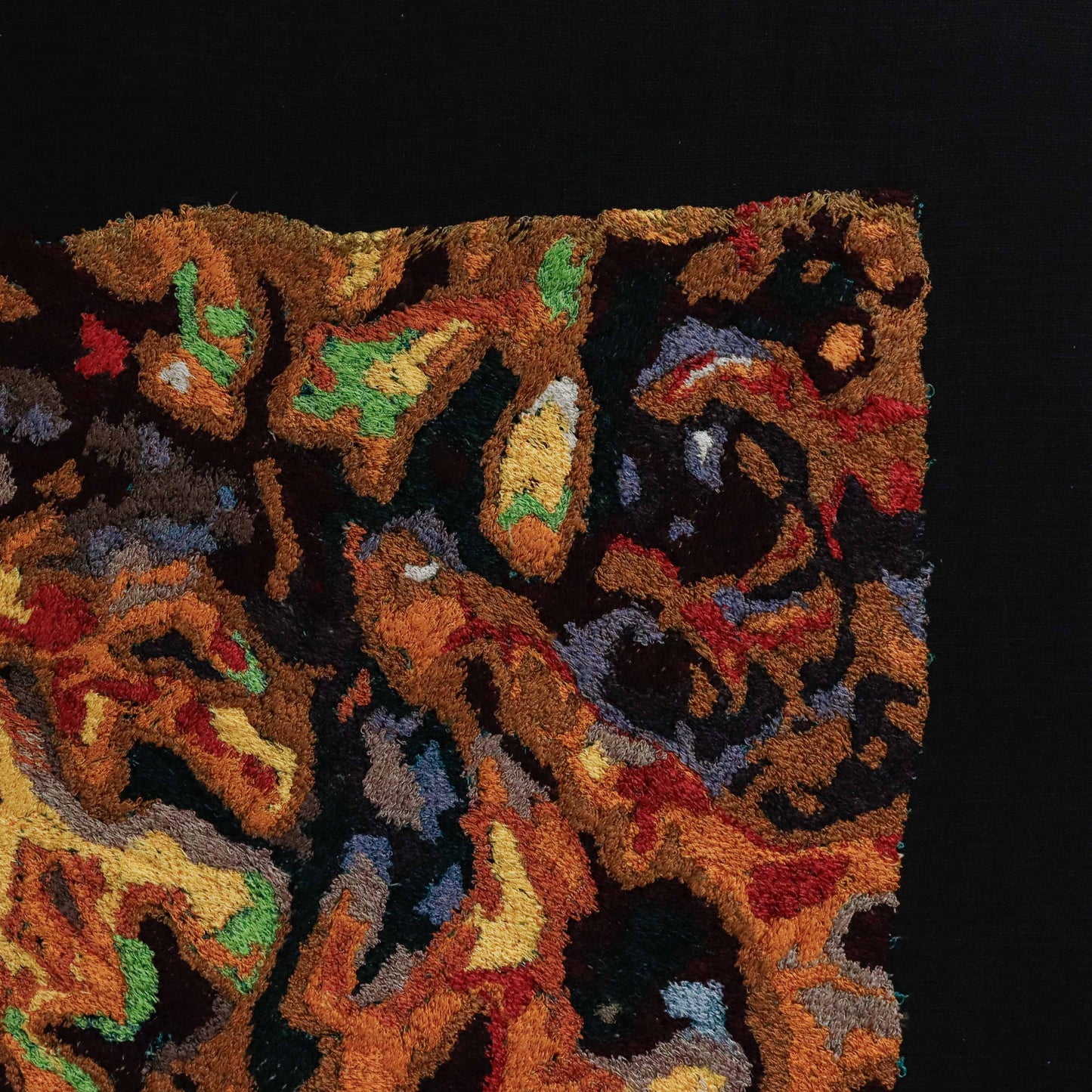 A close-up of a thread painting, showcasing detailed stitching with colorful thread forming abstract patterns.