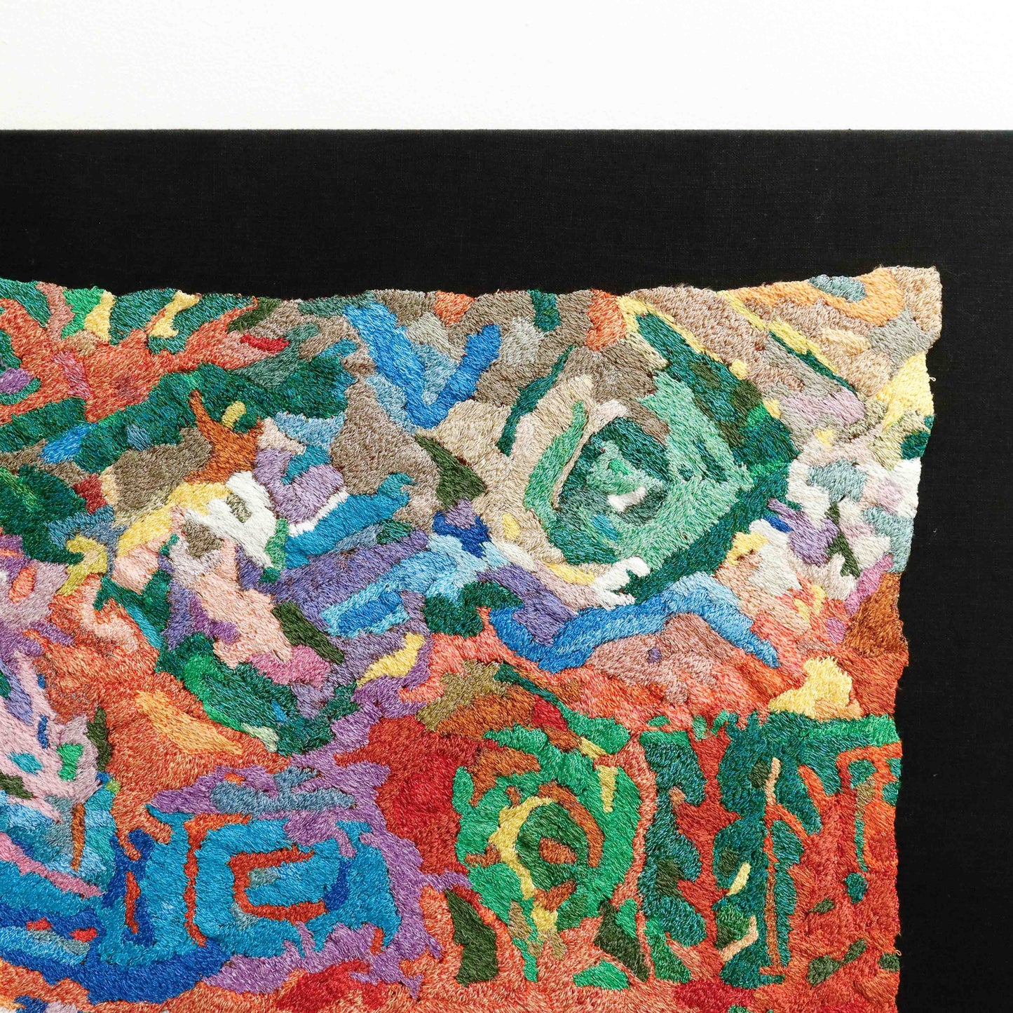 A close-up of a thread tapestry with abstract patterns, showcasing intricate stitching and colorful thread.