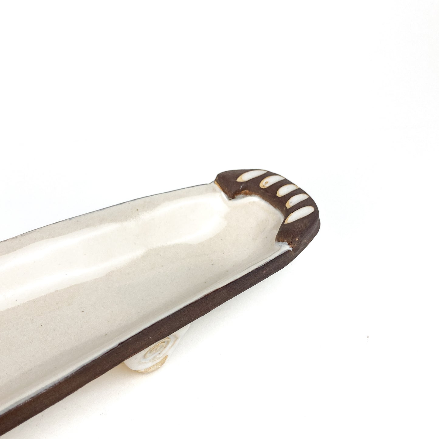 A close-up of an olive dish with raised details at one end.
