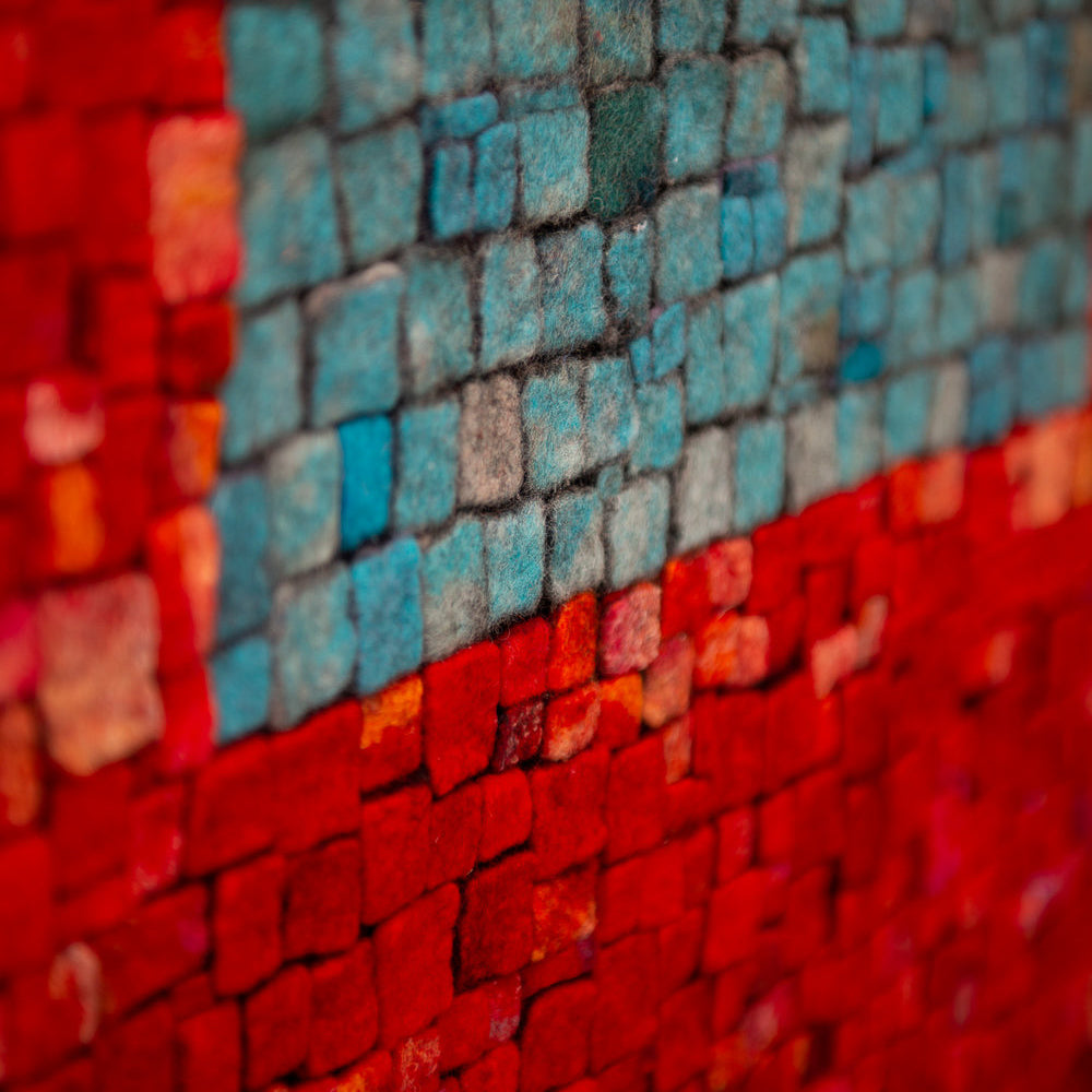 Textured mosaic art. A central blue square is surrounded by a red textured background.