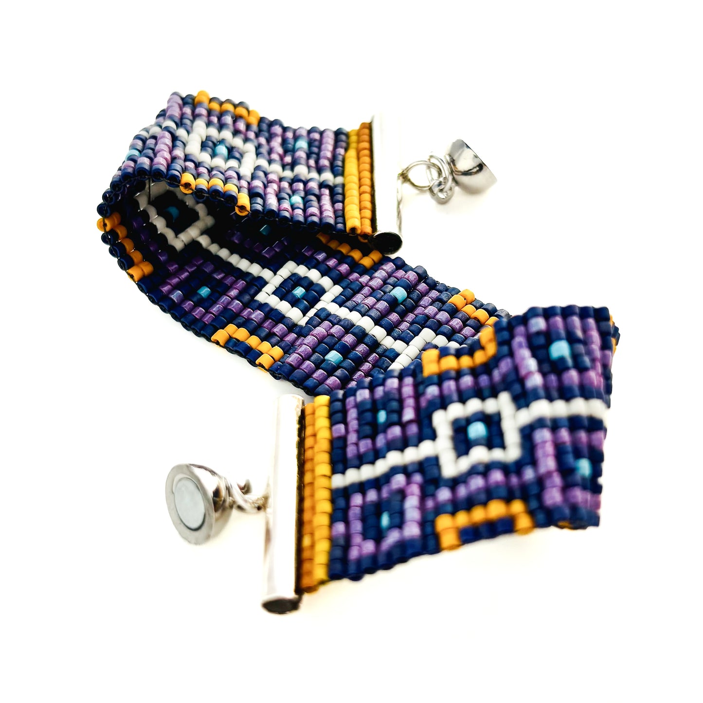 A beaded bracelet with a geometric pattern in purple, blue, orange, and white has a silver magnetic ball clasp.