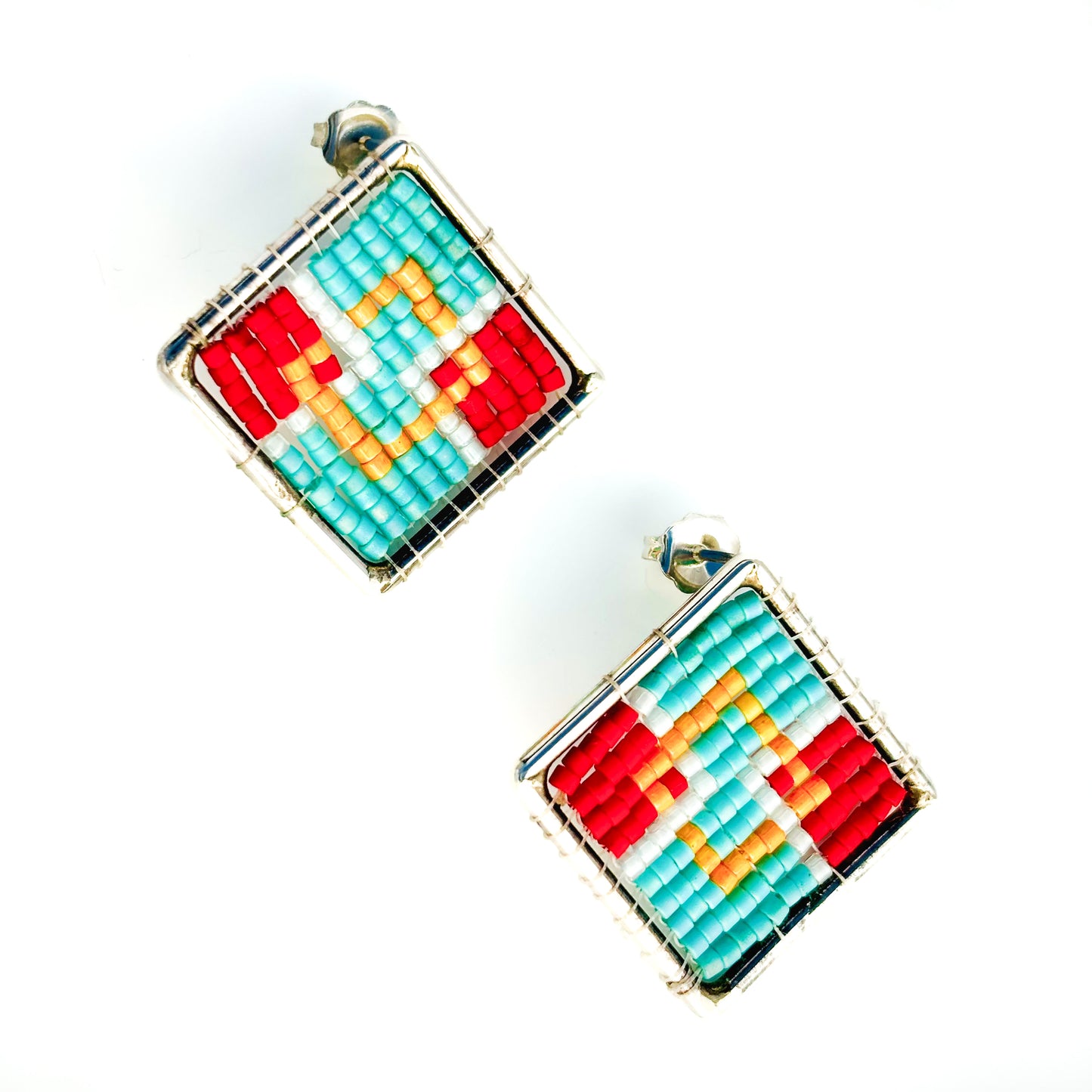 Two square stud earrings feature a colorful geometric beadwork design in red, orange, turquoise, and white within silver frames.