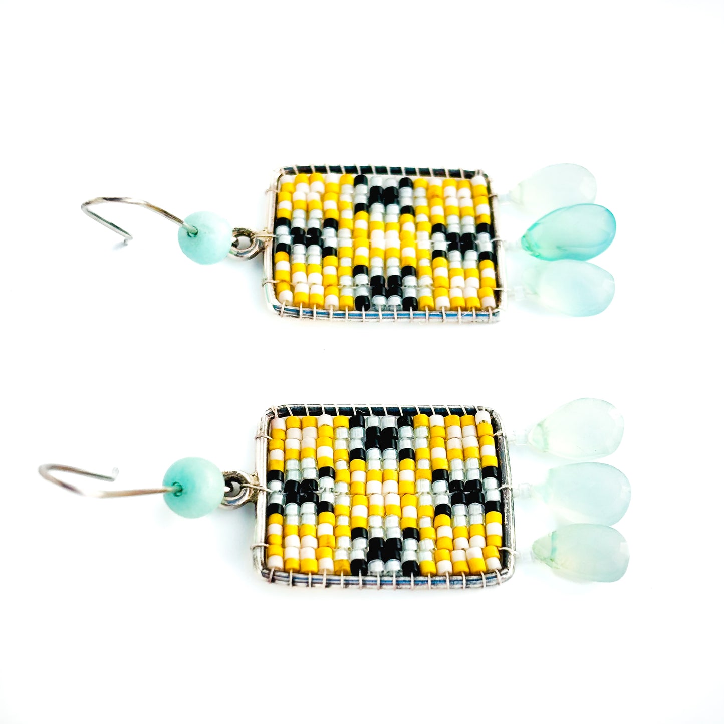 Two rectangular dangle earrings feature a yellow, white, and black beaded pattern with pale blue teardrop charms and beads.