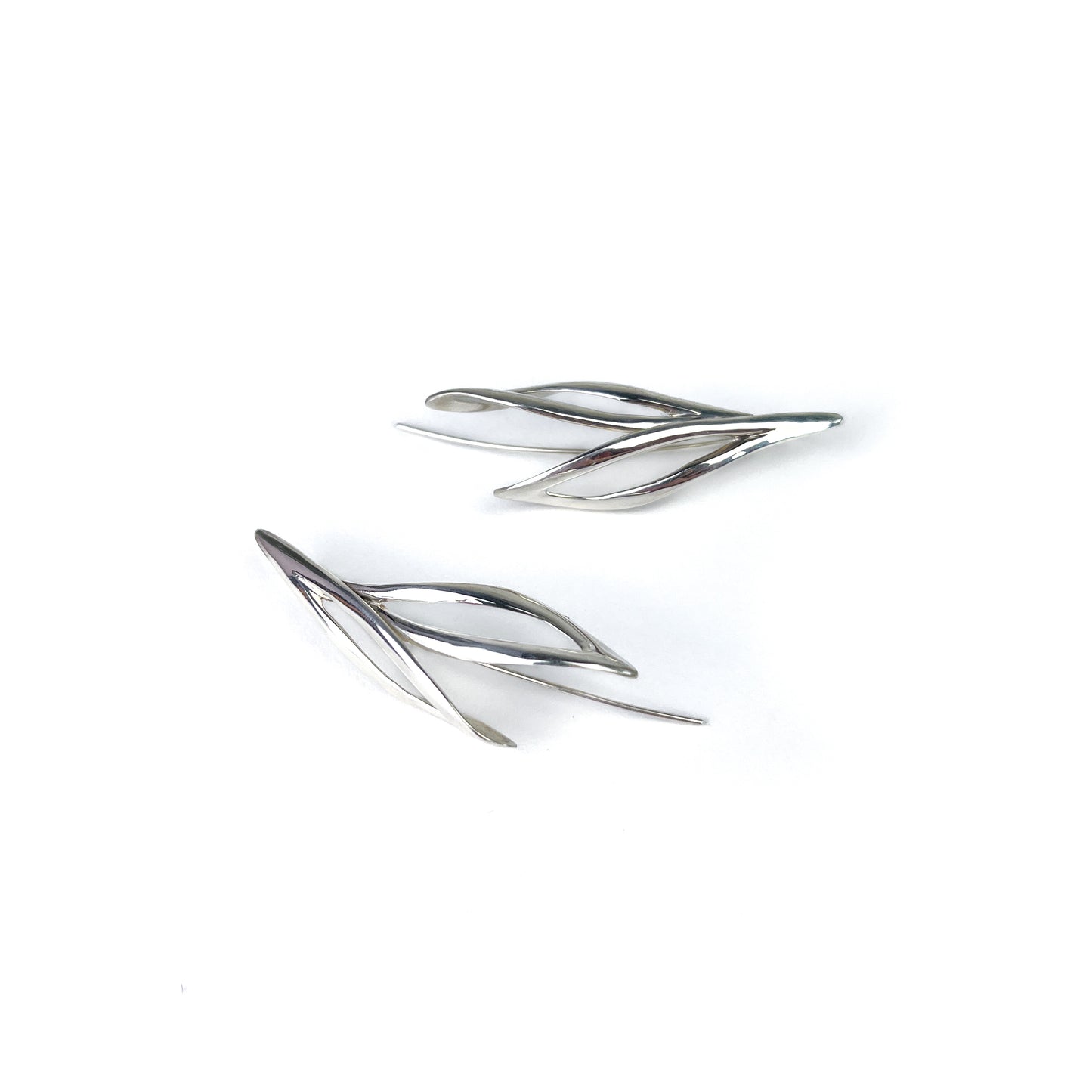Two shiny silver willow earrings, lying flat showing their sleek, leaf-like shape.