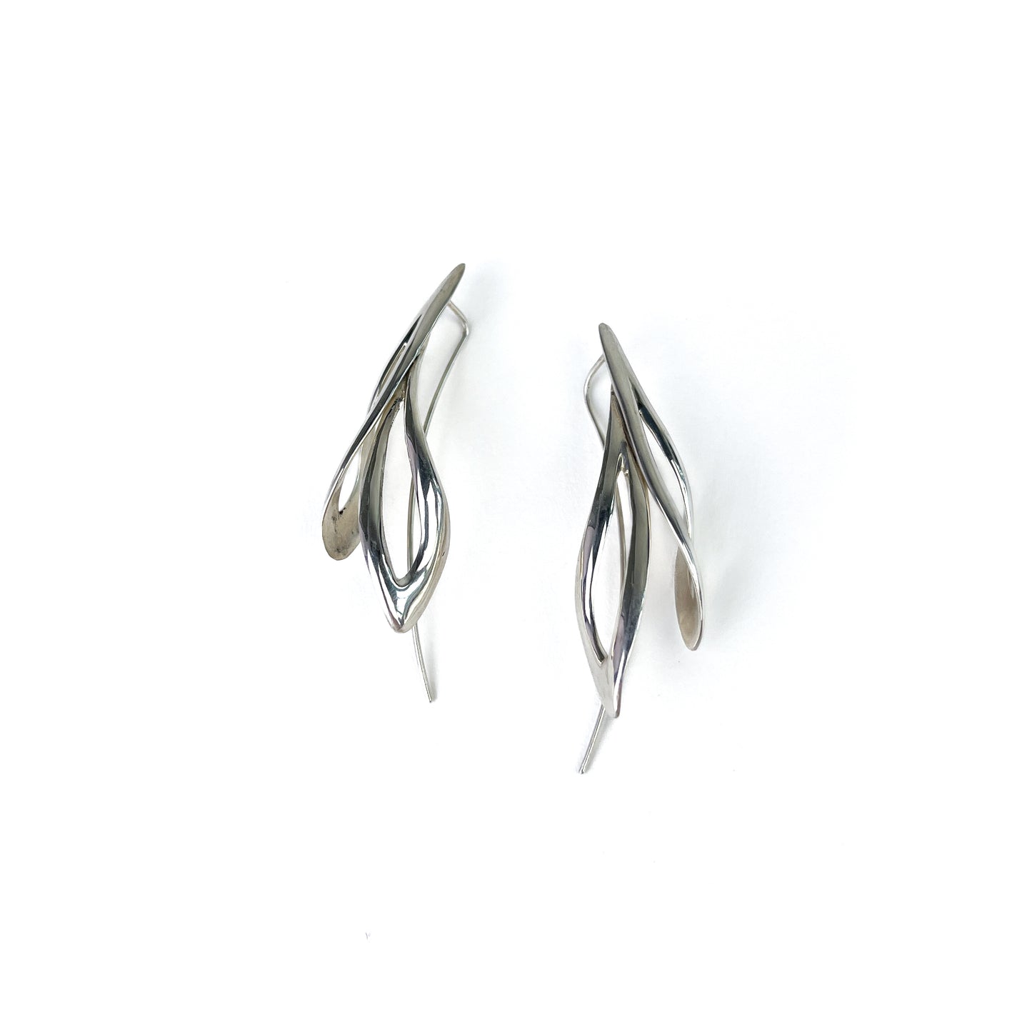 Close-up of a pair of shiny silver willow earrings, highlighting their elegant, flowing form.
