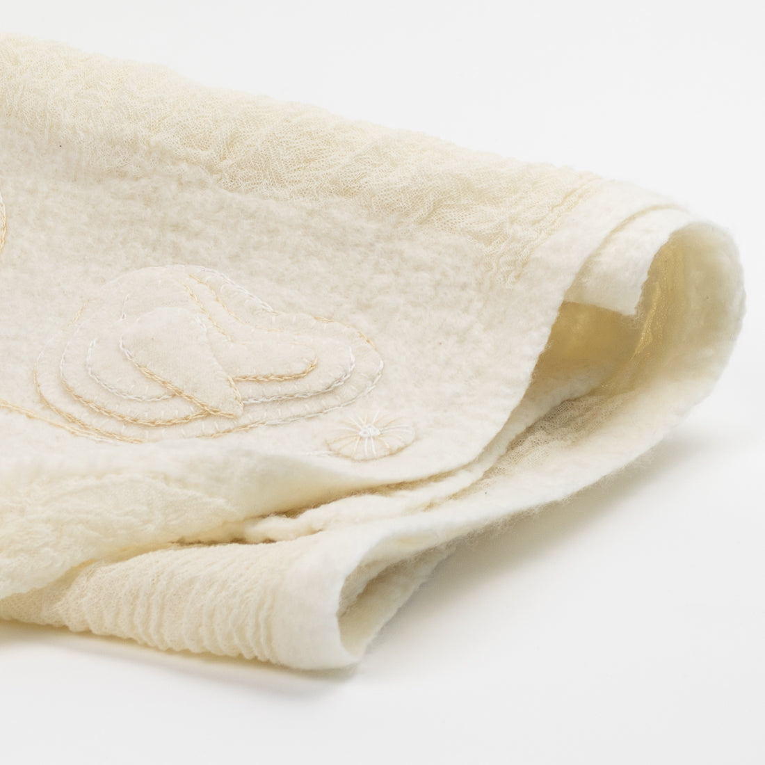 Close-up of a Merino wool shawl reveals the texture and delicate floral embroidery.