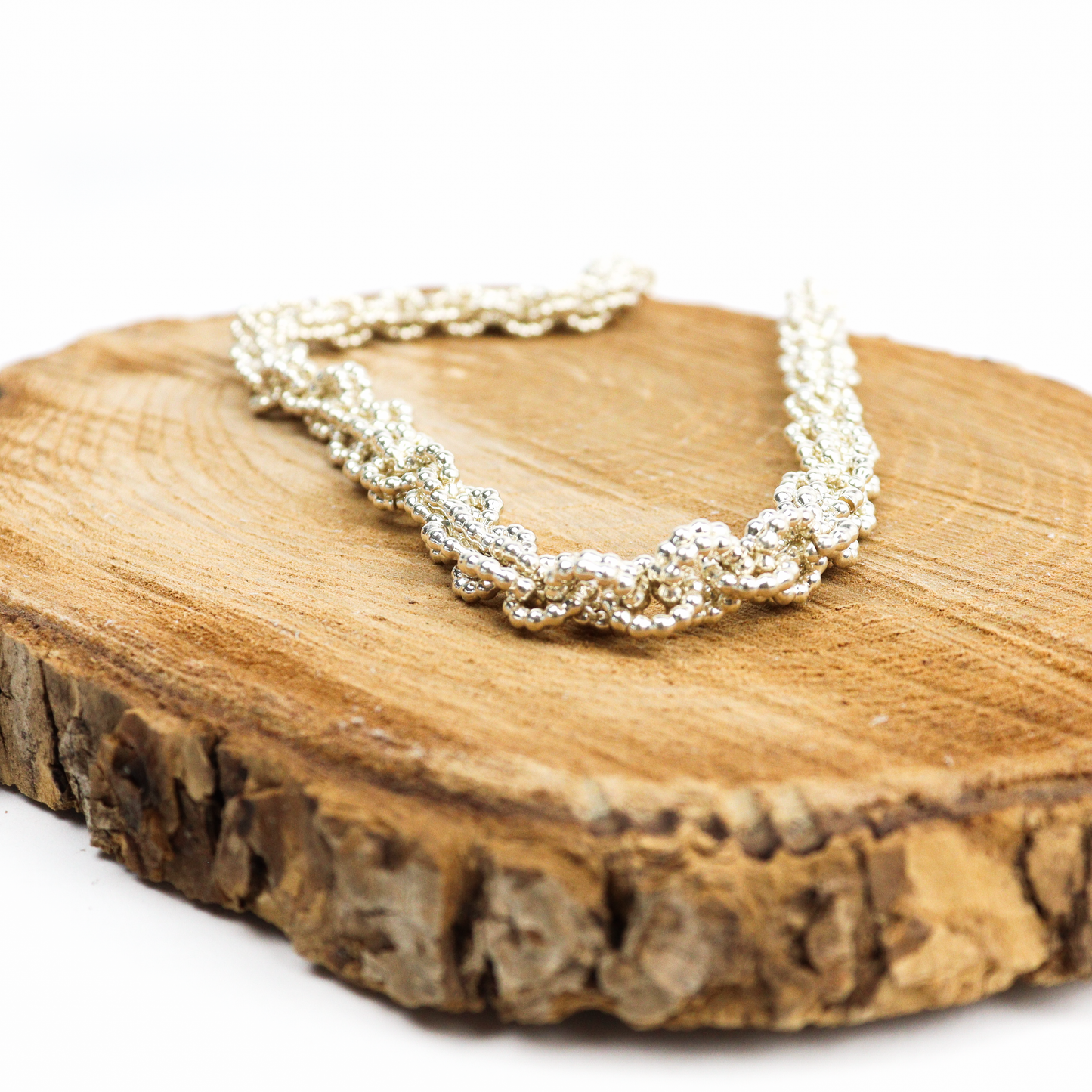 Chain Mail Necklace displayed on a wooden surface, showcasing detailed interlinked silver rings