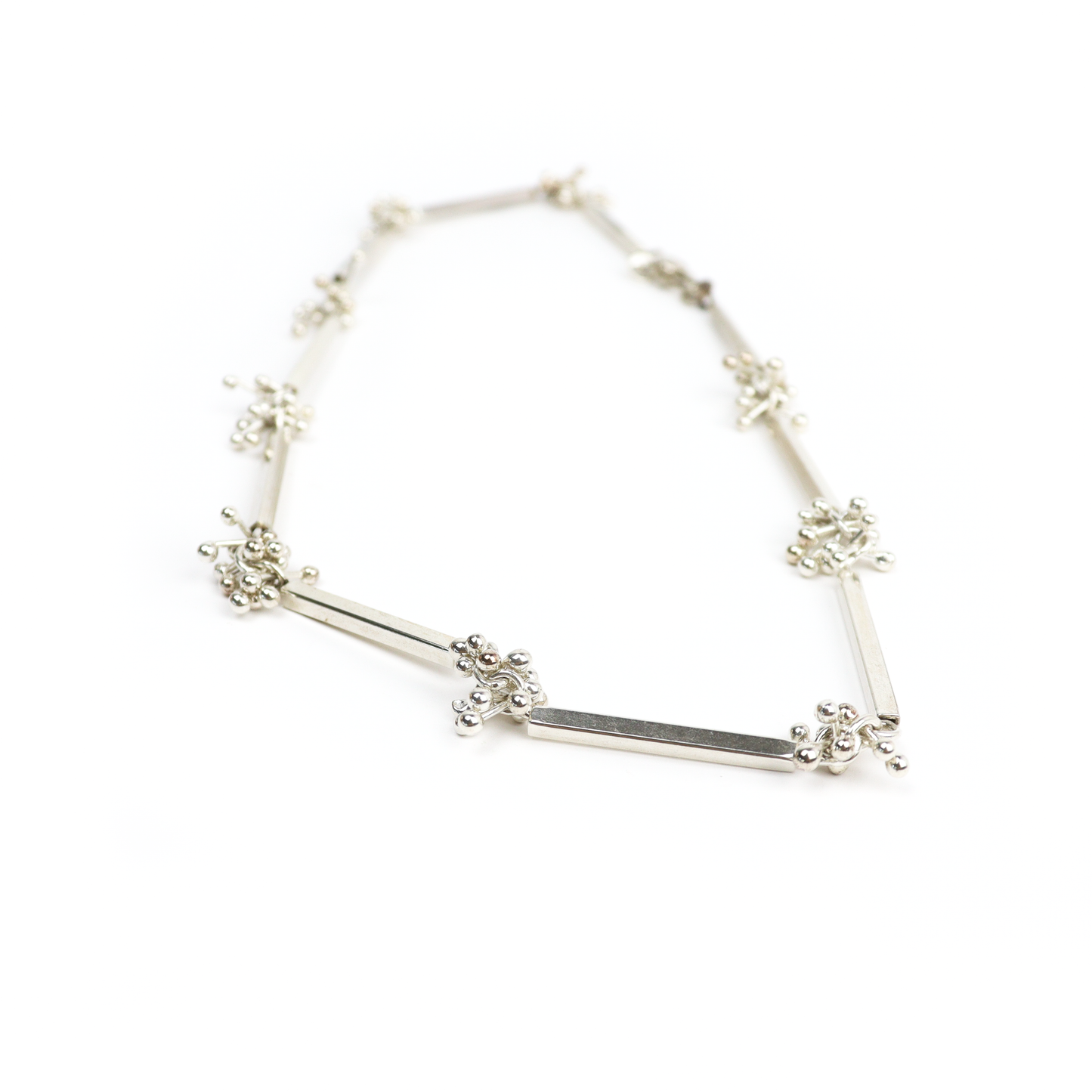 Angled view of Square Tube Barbell Necklace with polished silver bars and decorative ball clusters.