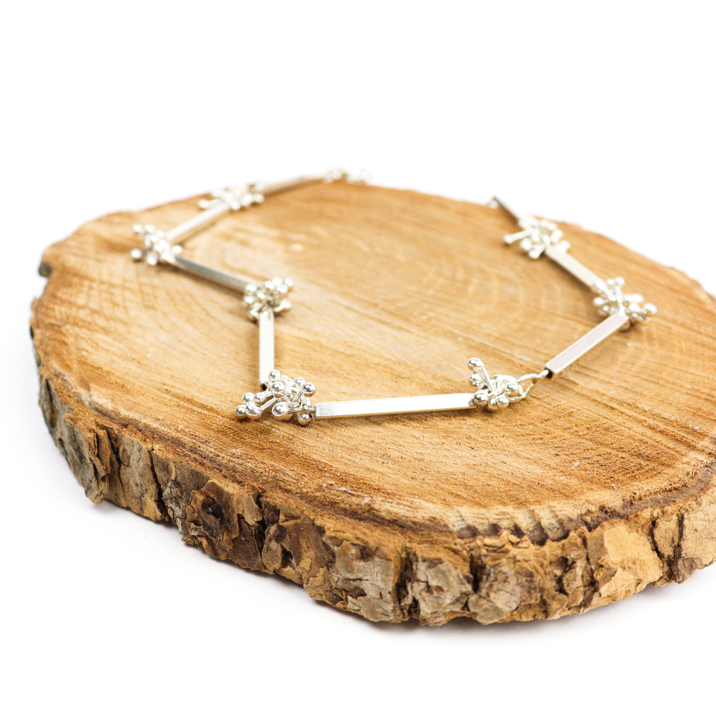Square Tube Barbell Necklace displayed on a wooden surface, showcasing silver bars and ball accents.