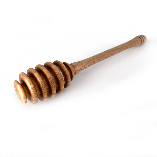 A wooden honey dipper with a grooved head.