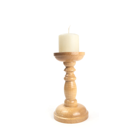 A light wooden candle holder with a white candle on top.